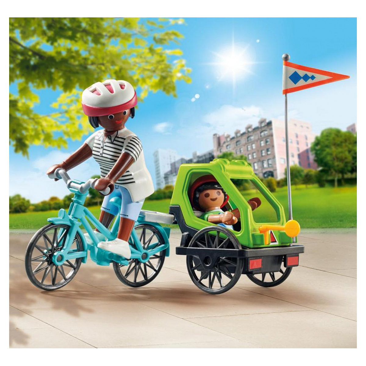 Kobieta jedzie na rowerze, ciągnąc zieloną przyczepkę z dzieckiem i flagą.