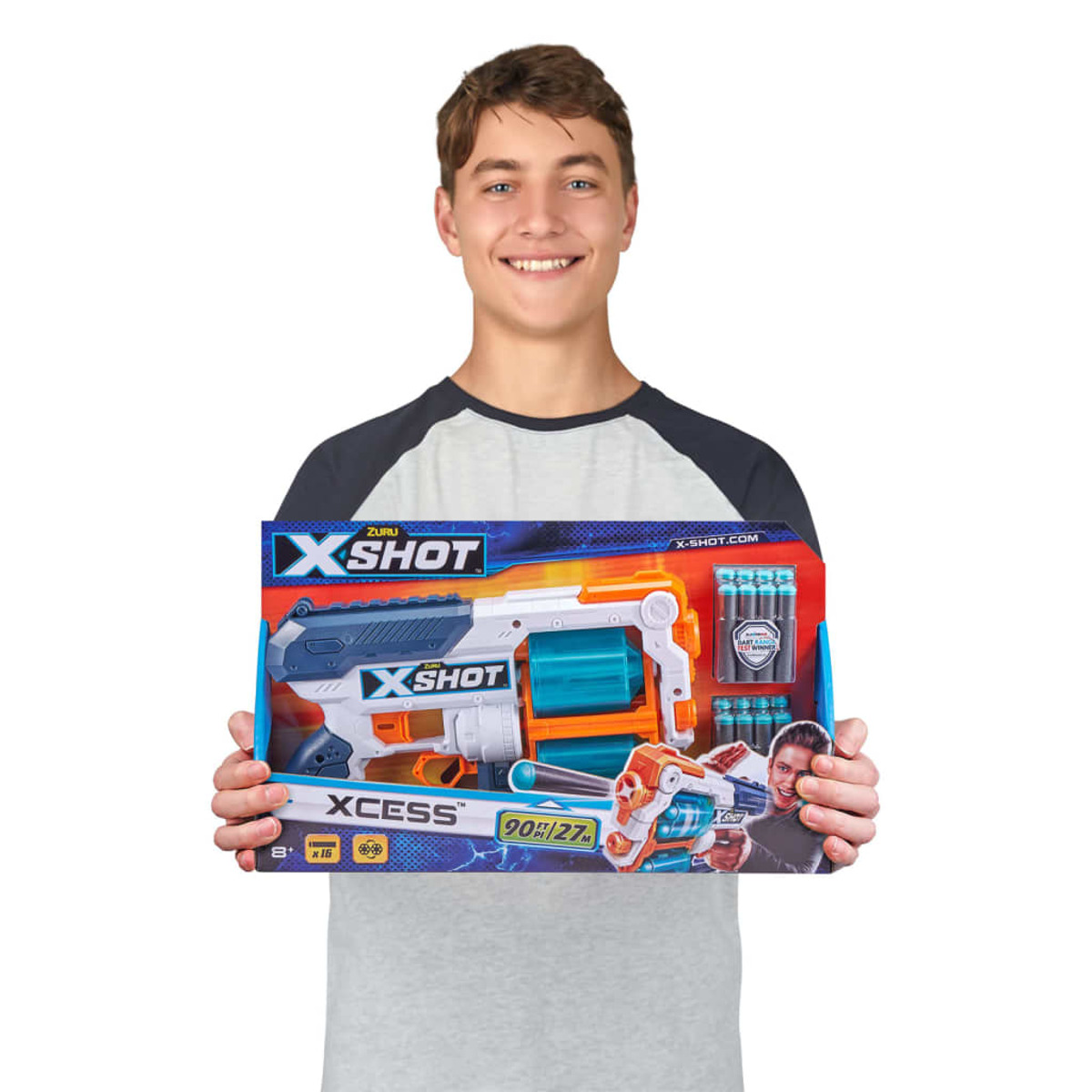 Ein junger Mann hält eine X-Shot Spielzeugpistolenbox und die Pistole. Die Box hat die Pistole, Munition und ein Bild.