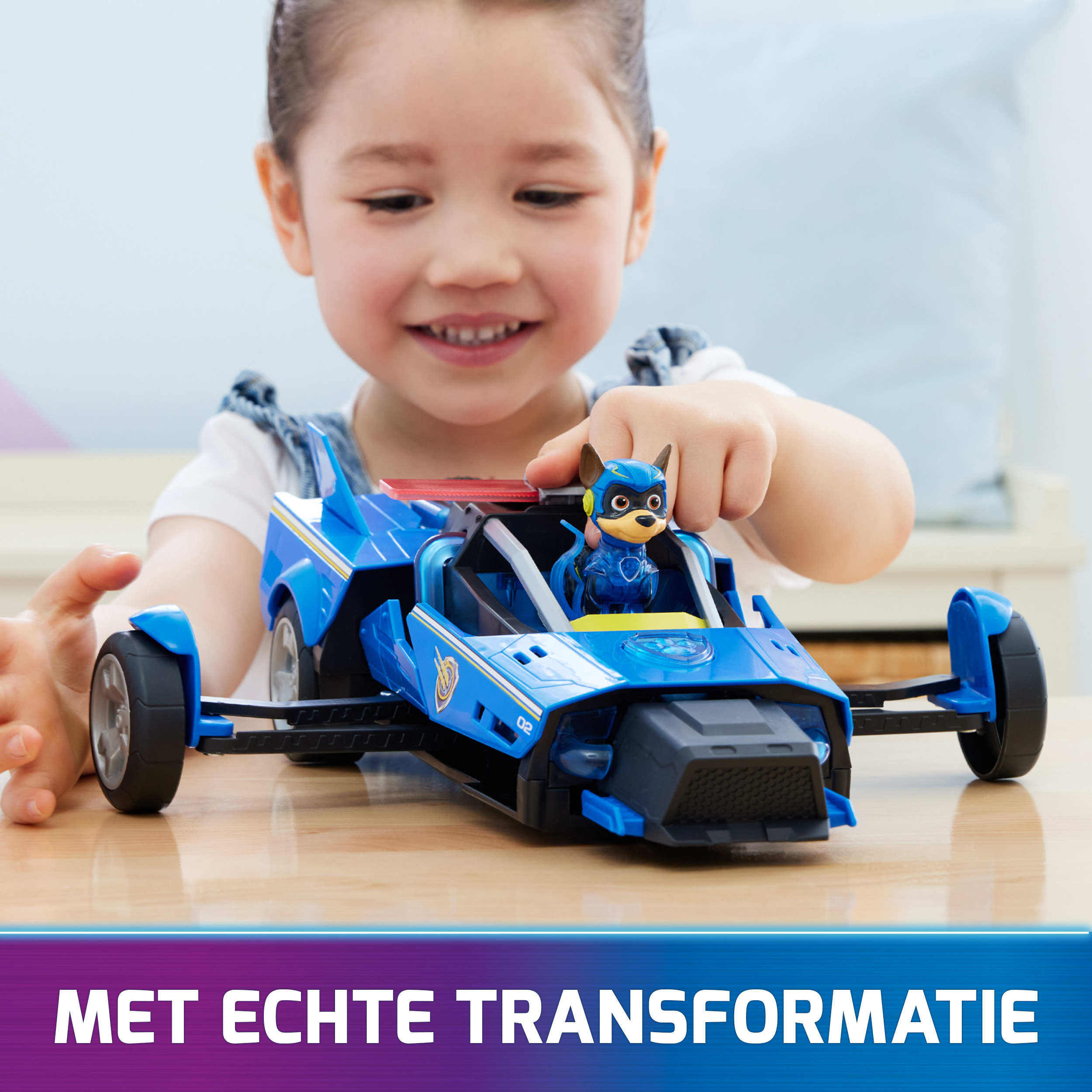 Niña jugando con un coche de juguete azul con figura de perro. Texto: Con transformación real.