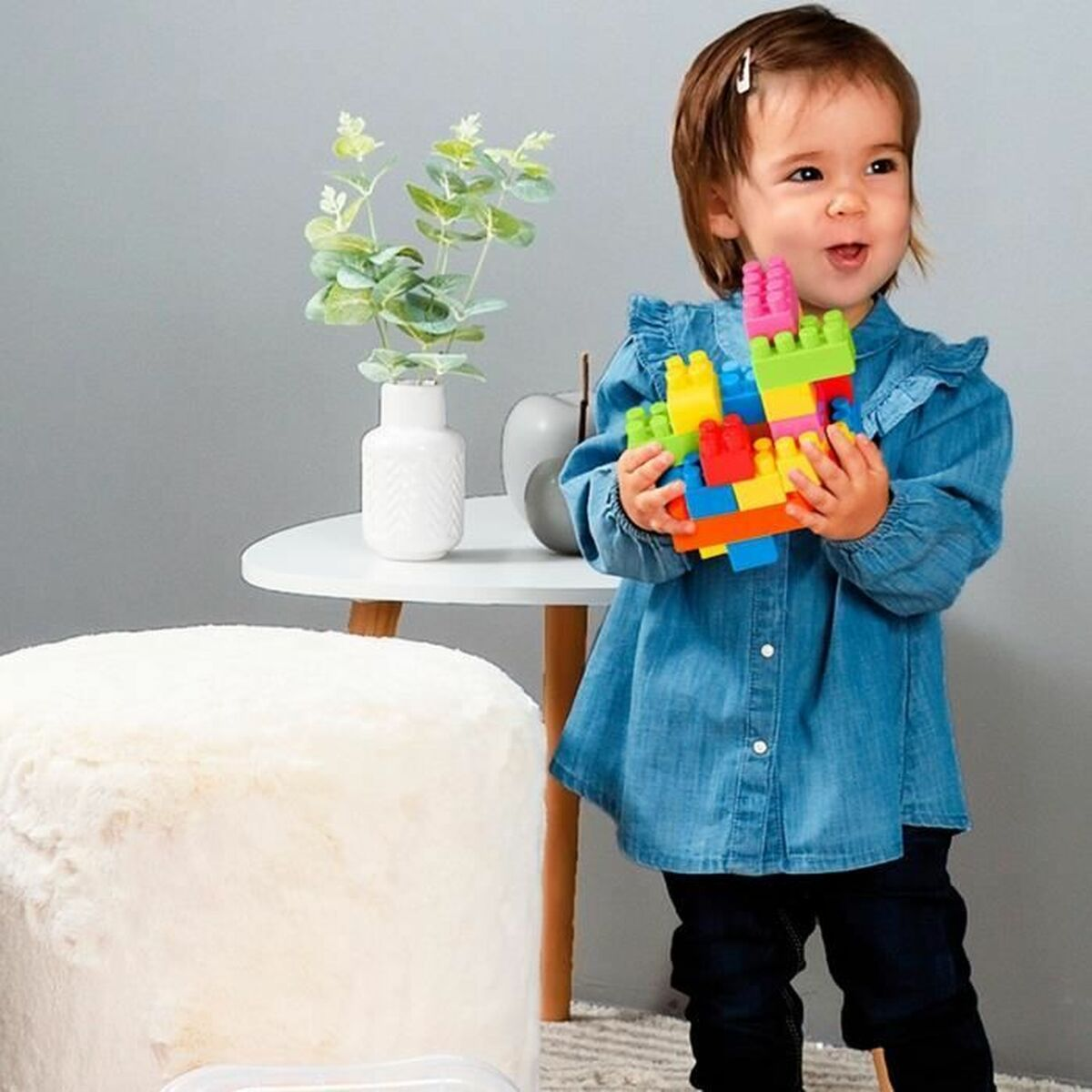 Una bambina tiene blocchi colorati. Sorride ed è al chiuso.