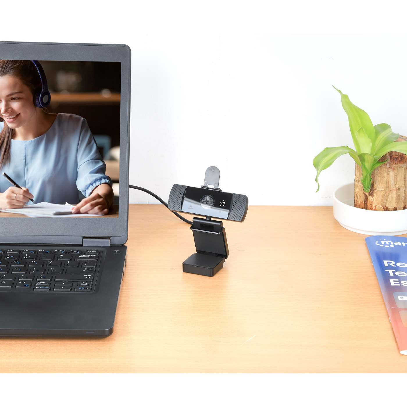 Webcam su una scrivania, collegata a un laptop, con una pianta.