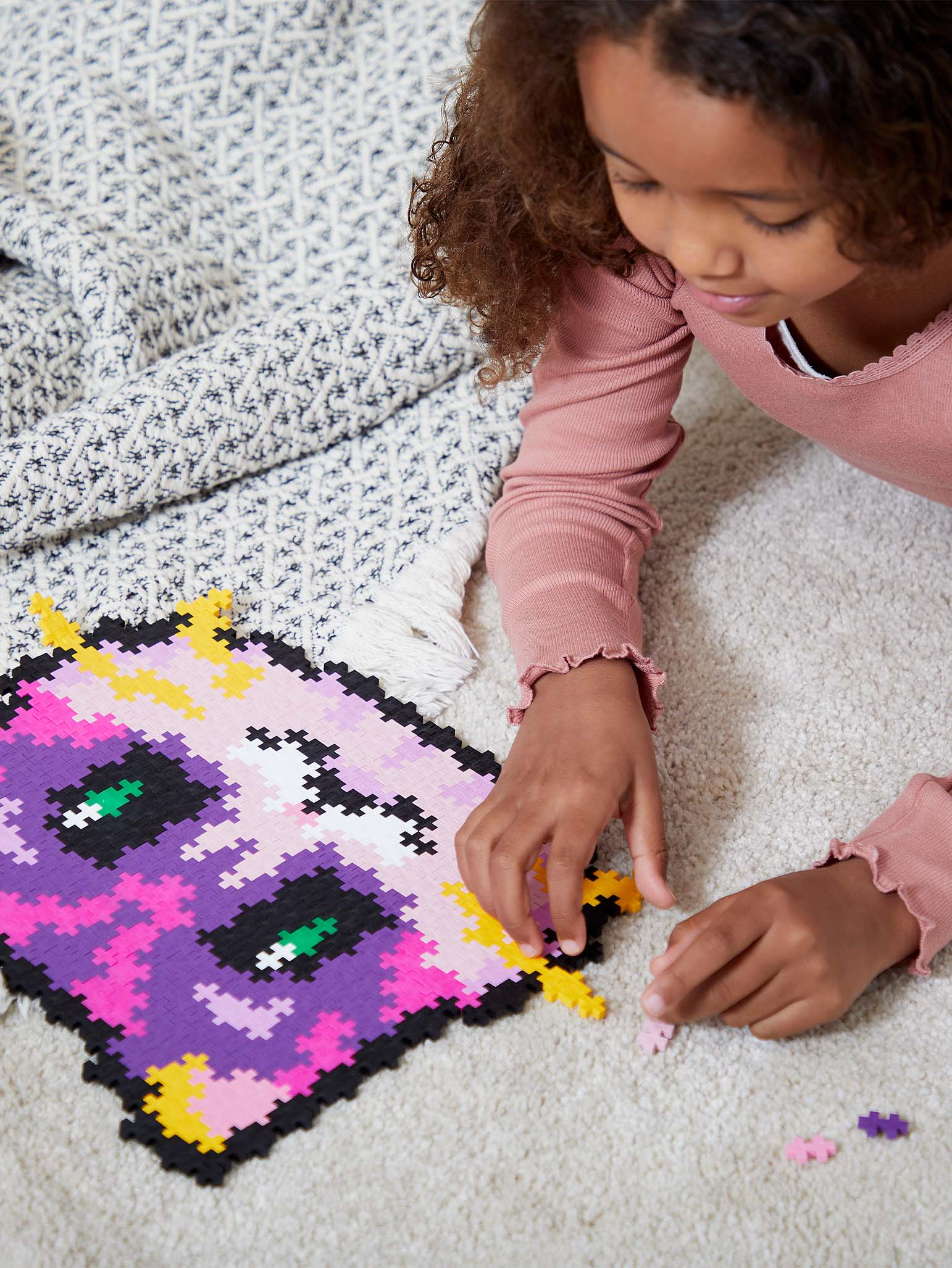 Dziewczynka układająca układankę z kotkiem po numerach. Układanka to pikselowy obrazek kota.