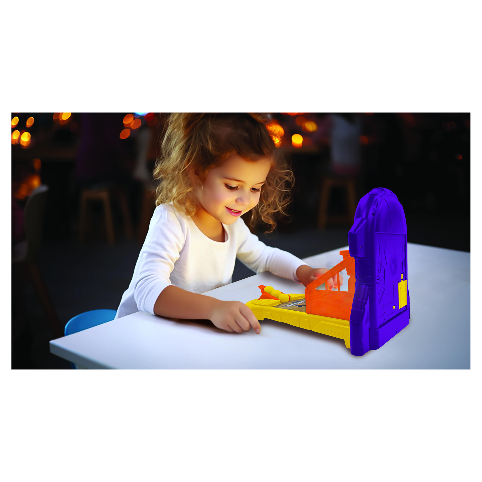 Una bambina gioca con un gioco di basket giocattolo su un tavolo. È giallo, arancione e viola.