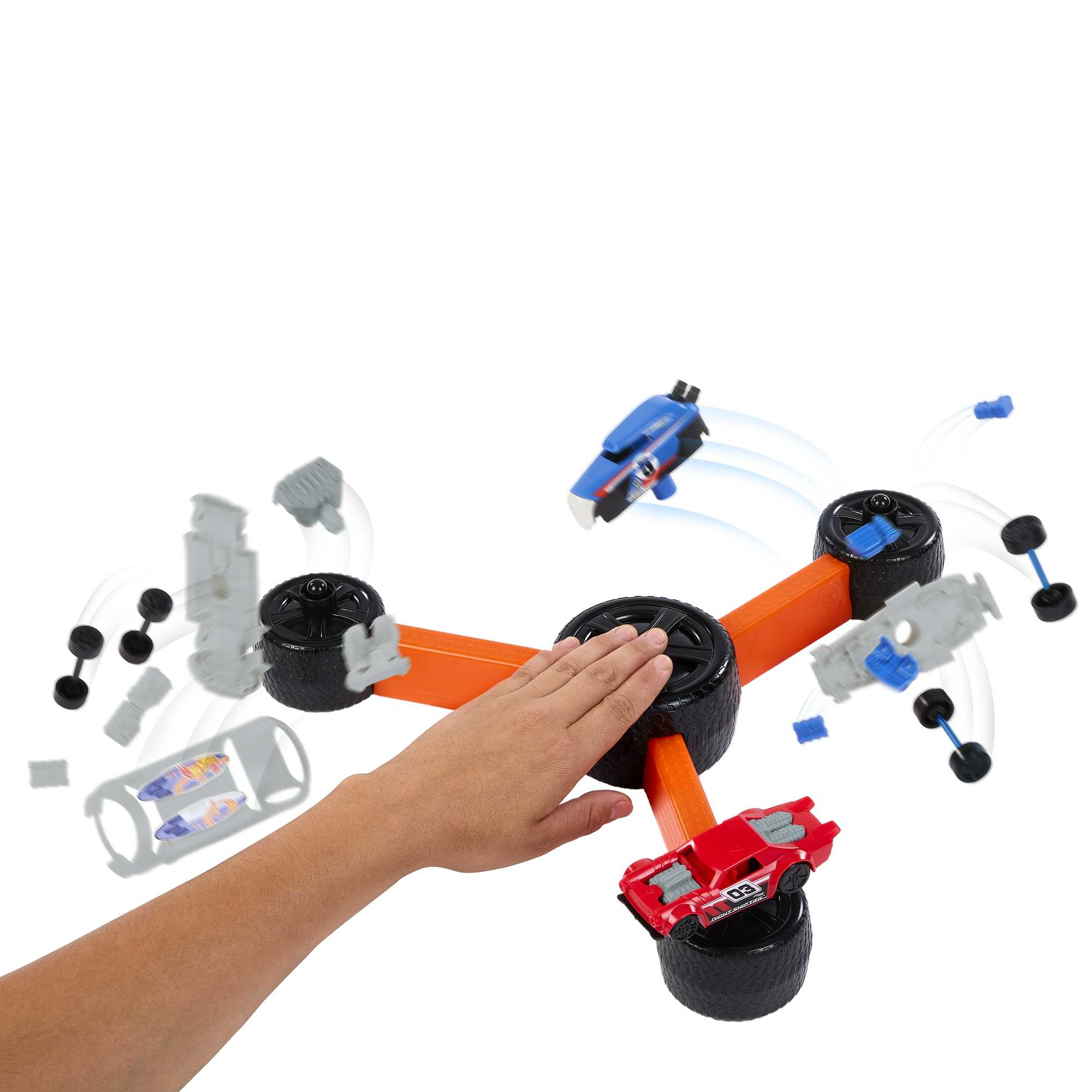Una mano activa un juguete Hot Wheels, los coches salen disparados de la pista.