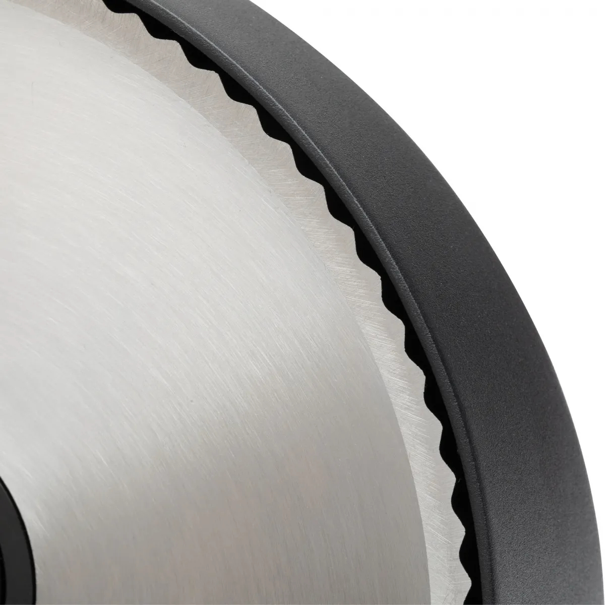 Zbliżenie na tarczę piły tarczowej. Tarcza jest srebrna z czarnymi zębami i czarną obwódką.