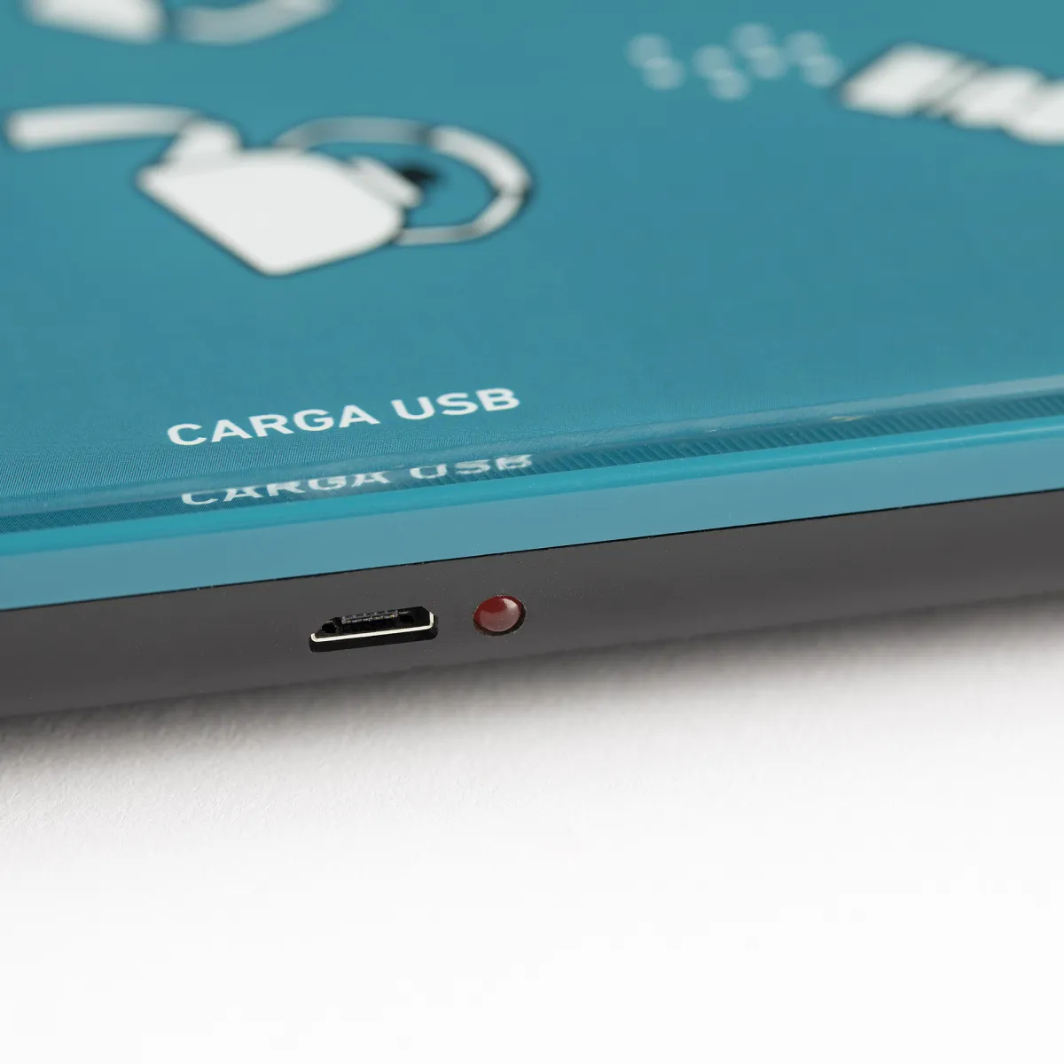 Una bilancia da cucina digitale turchese. Primo piano della porta di ricarica e un indicatore luminoso rosso. Testo: CARGA USB.