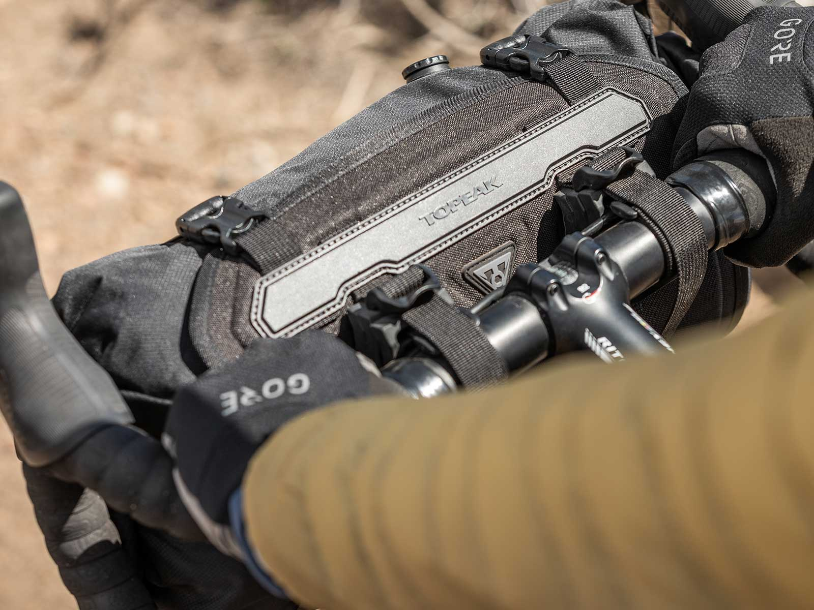 Zbliżenie kierownicy roweru i czarnej torby. Na torbie napis TOPEAK.