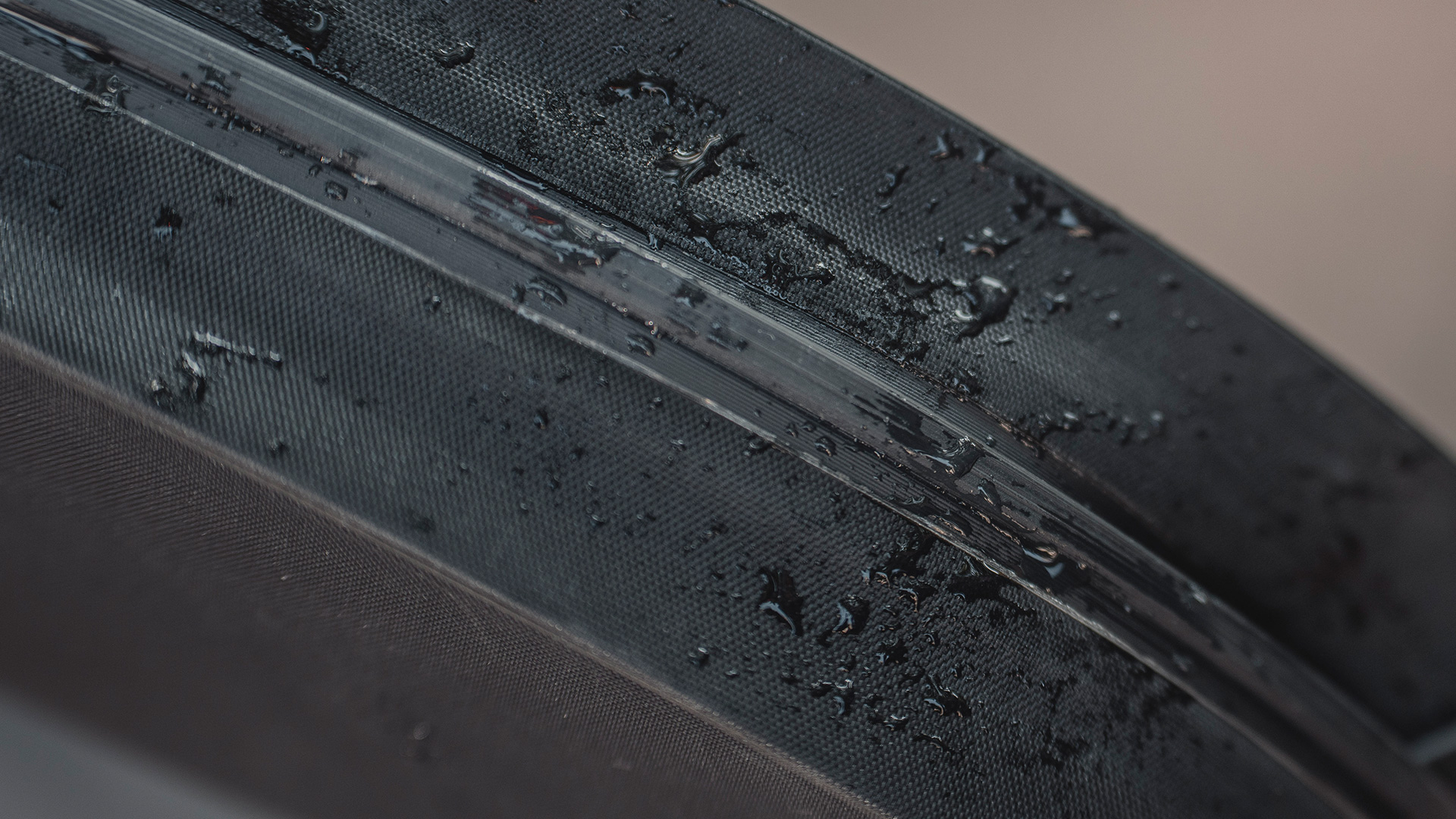Zbliżenie czarnej torby z kroplami wody, widoczna tekstura.