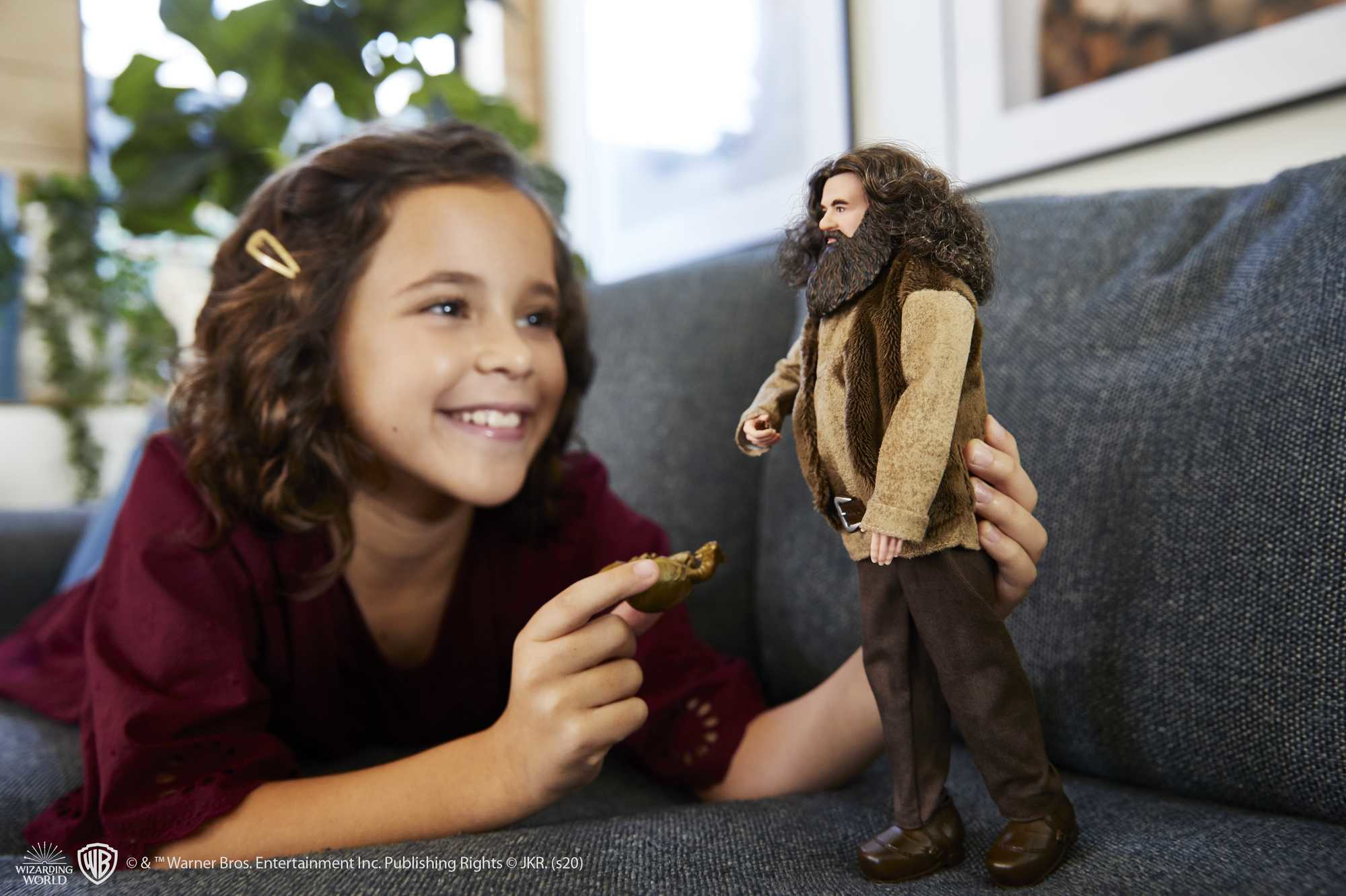 Una ragazza sorride a una bambola di Hagrid. La bambola tiene un biscotto in una stanza.