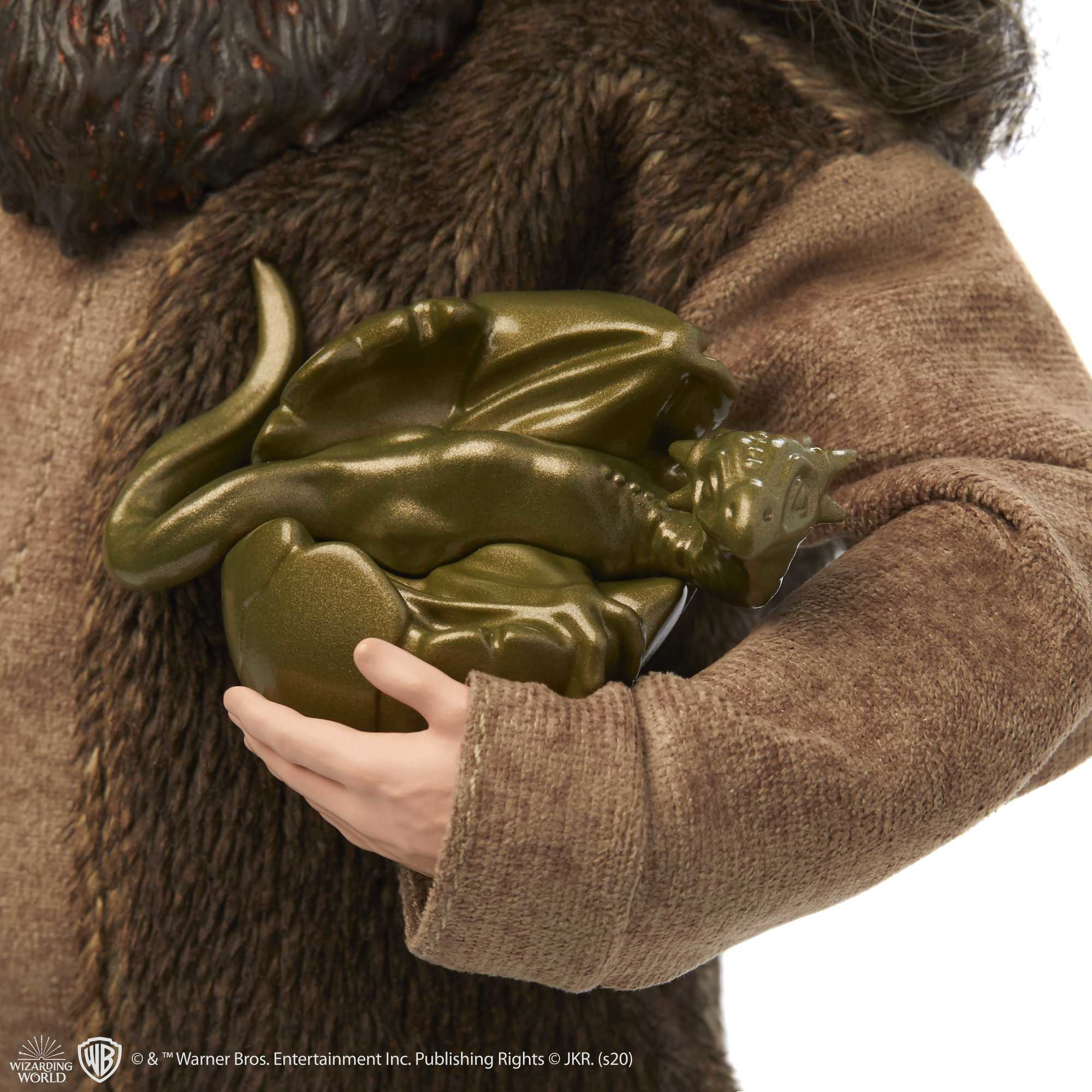 Persona che tiene una figura di drago verde, cappotto di pelliccia marrone.