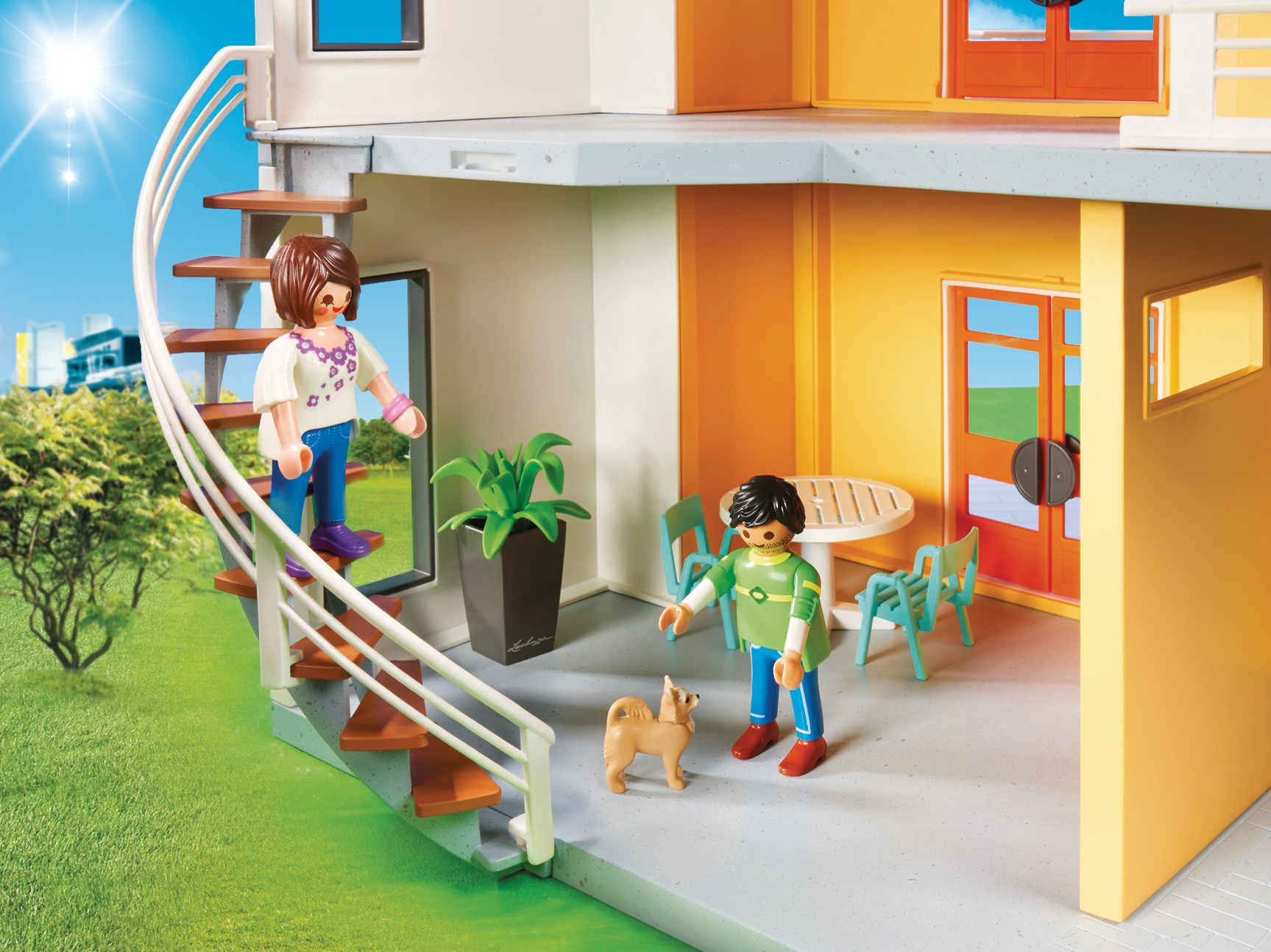 Scena Playmobil z figurkami, psem i wnętrzem domu. Kobieta schodzi po schodach. Zielona trawa na zewnątrz.