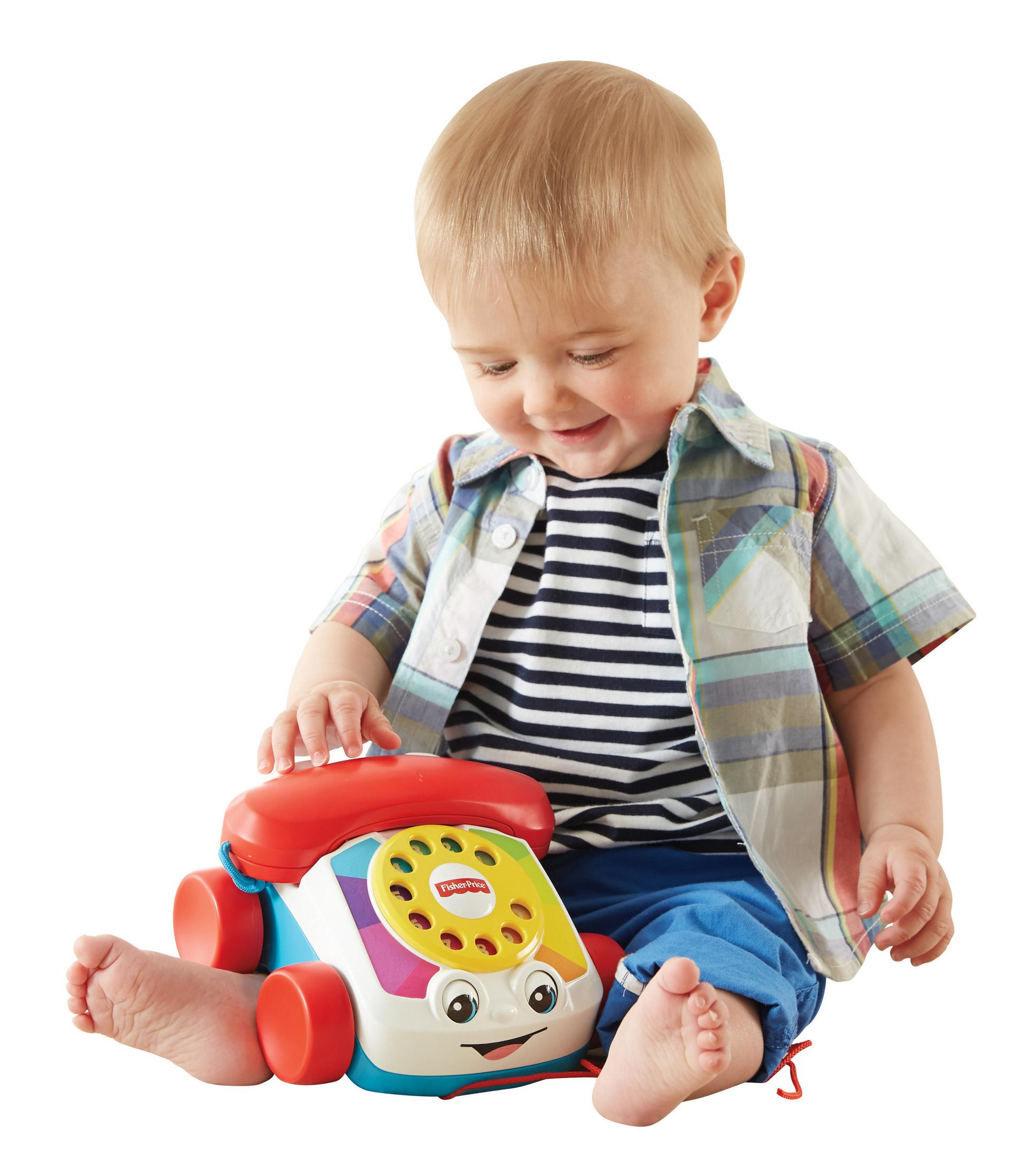 Dziecko siedzi bawiąc się kolorowym telefonem-zabawką Fisher-Price.