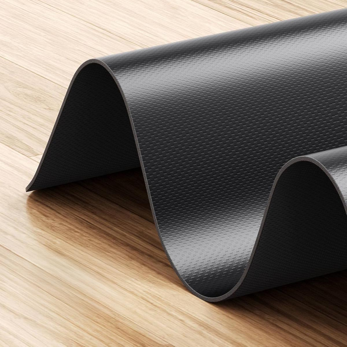 Un primo piano di un tappetino nero con superficie strutturata, parzialmente arrotolato. Il marchio WalkingPad è stampato.