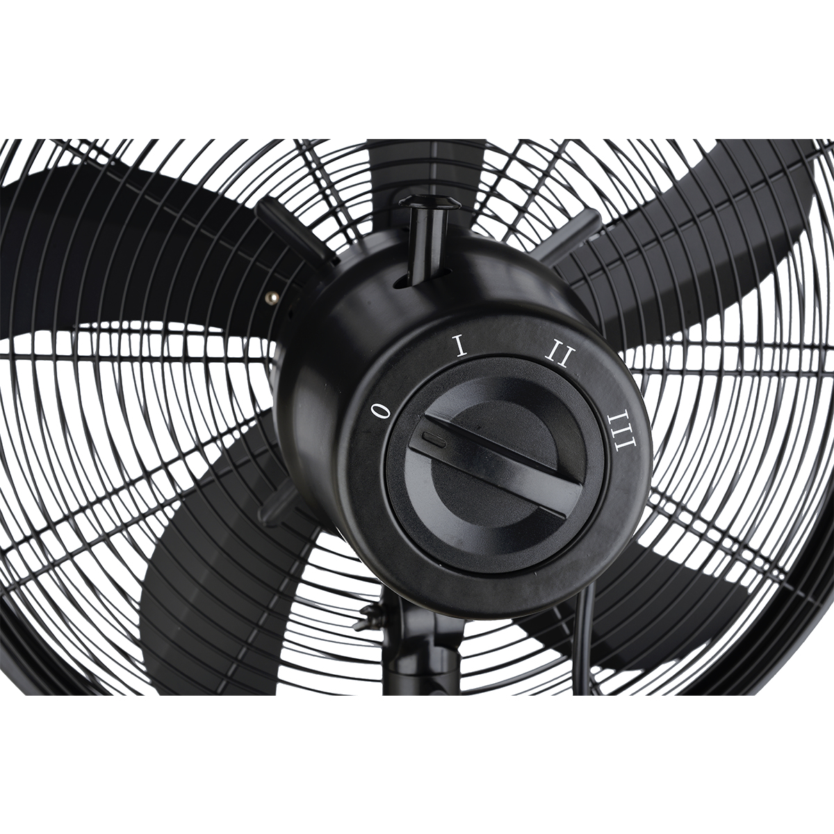 Primo piano delle pale nere del ventilatore, con un quadrante di controllo con etichetta 0, I, II, III. Il quadrante controlla la velocità.