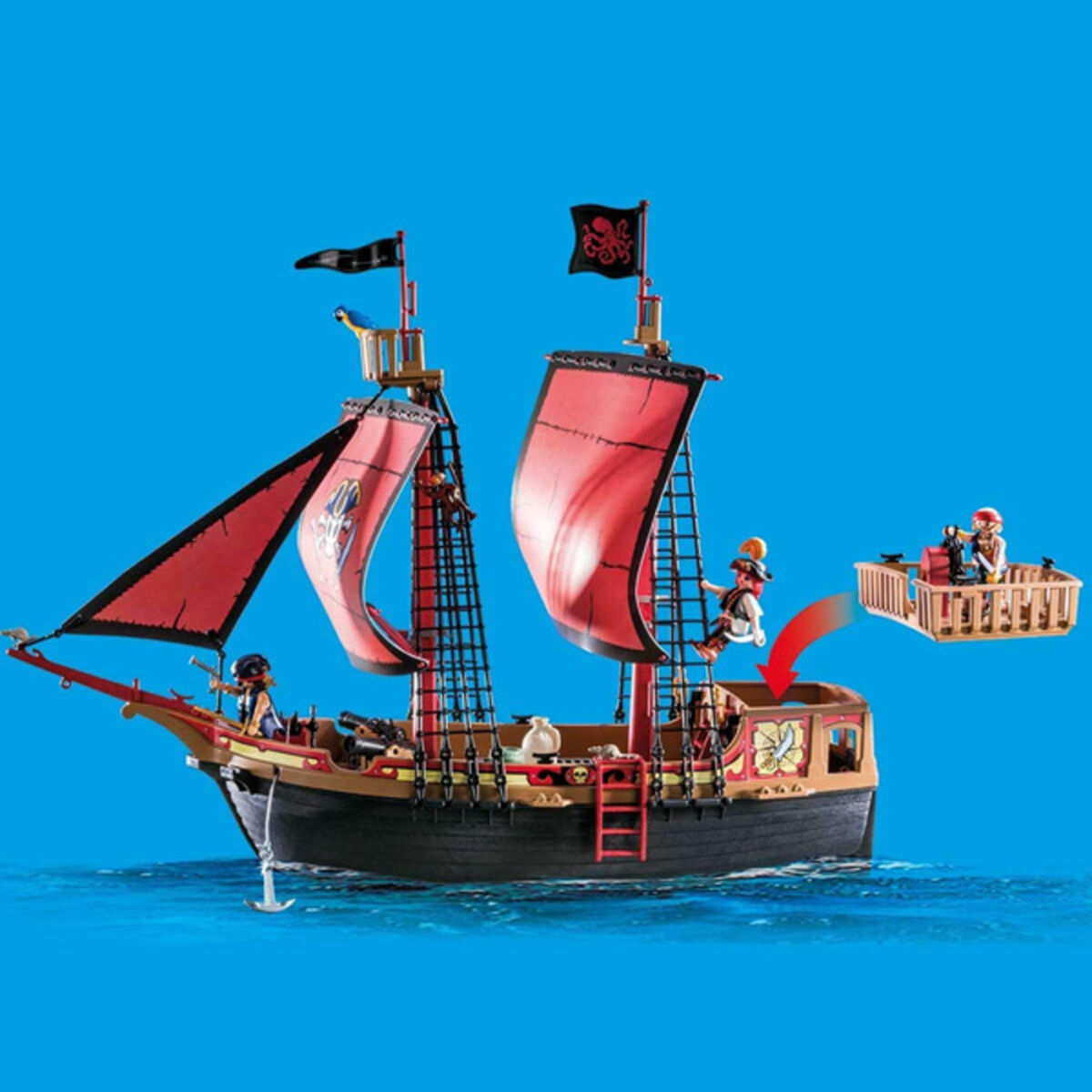 Una nave pirata giocattolo su acqua blu. Ha vele rosse, figure e una piccola barca.