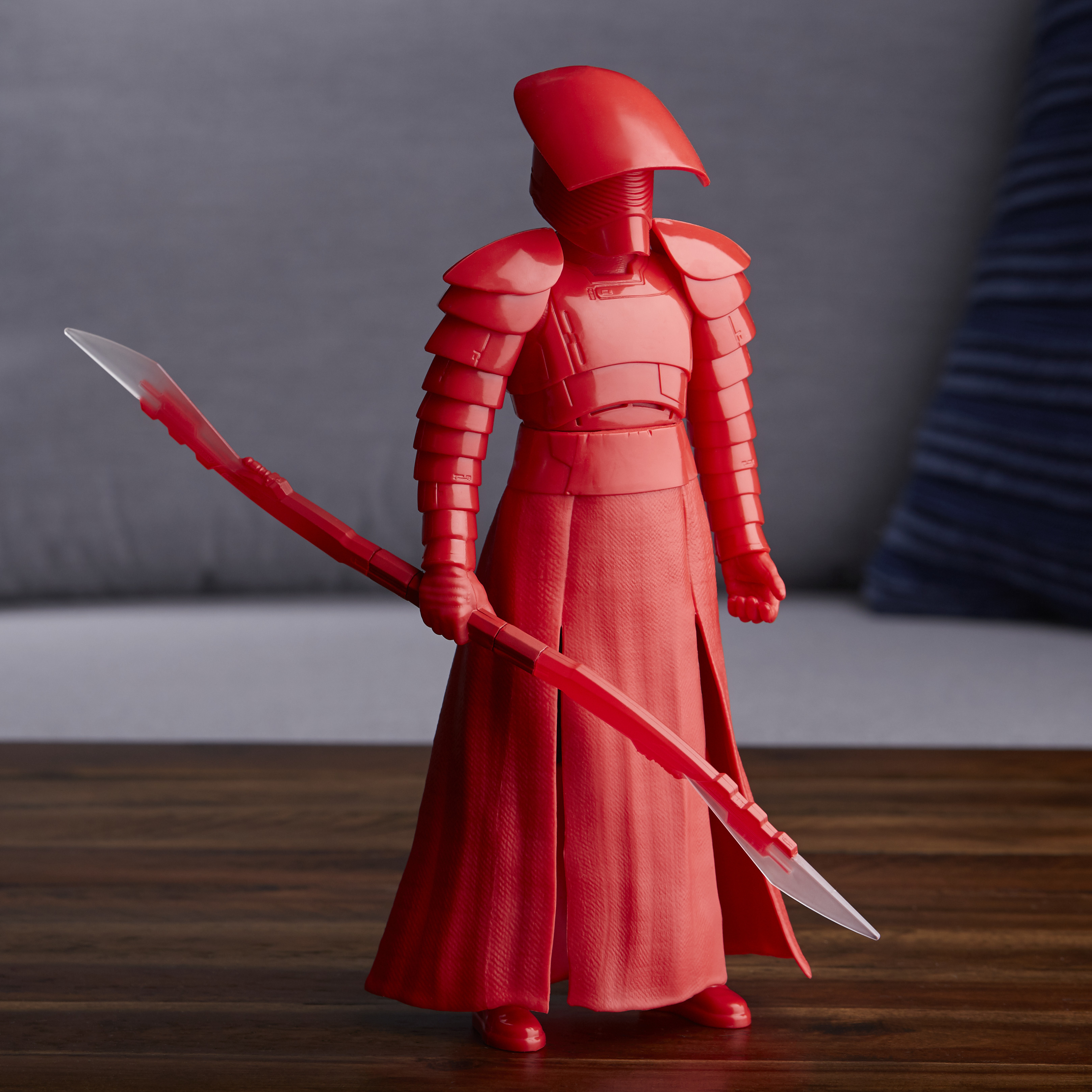 Una statuetta rossa di Praetorian Guard tiene un bastone rosso, su sfondo grigio.