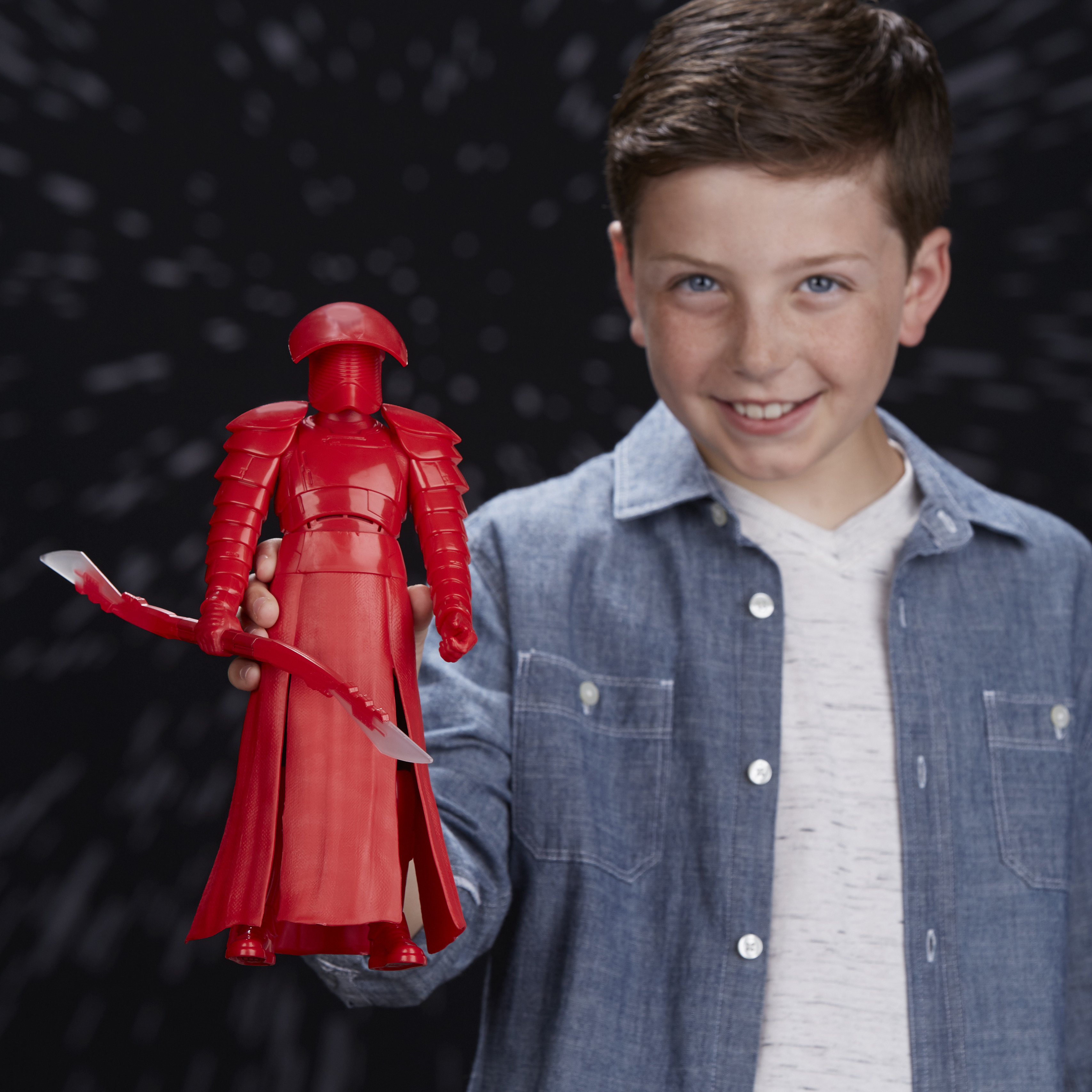Un ragazzo che tiene in mano una figura rossa di Star Wars, vestita con armatura, elmo e un'arma.