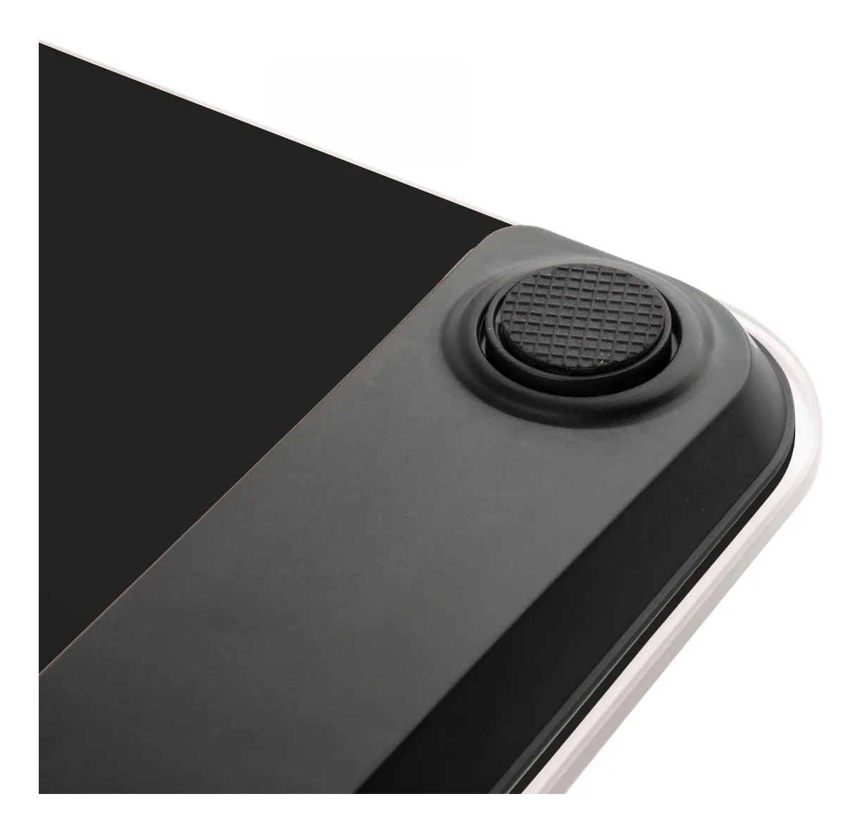 Zbliżenie rogu wagi cyfrowej, pokazujące czarną powierzchnię i gumową podkładkę.