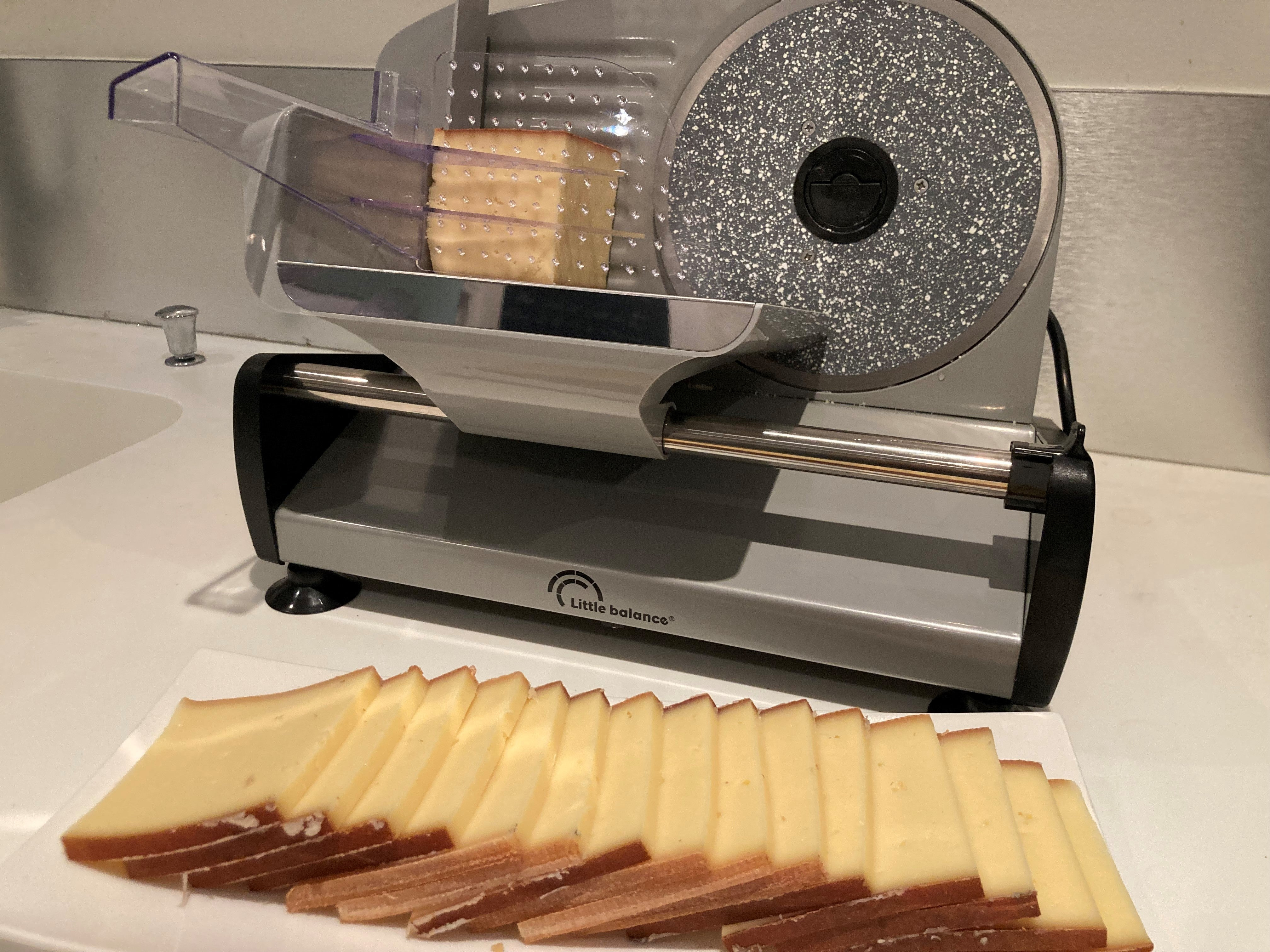 Krajalnica do sera z blokiem sera w trakcie krojenia, pokrojony ser z przodu.