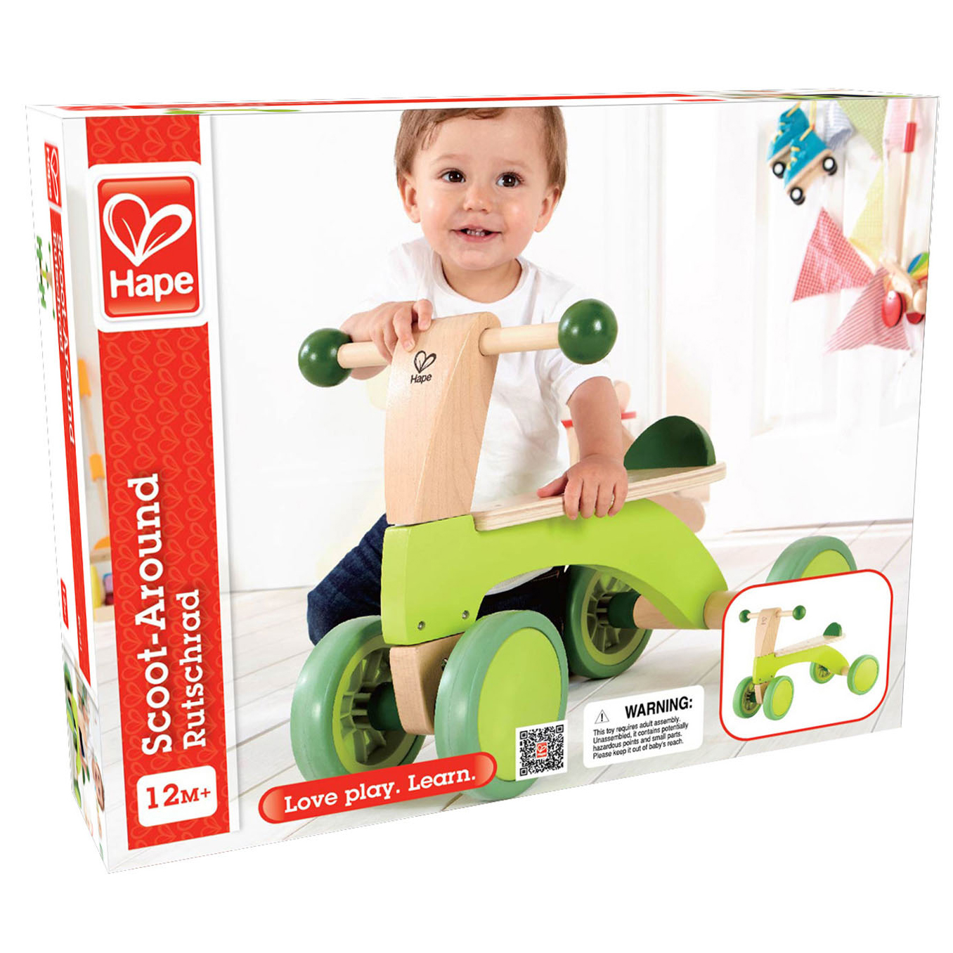 Un bambino è seduto su un giocattolo Scoot-Around verde e di legno. La scatola è sullo sfondo.
