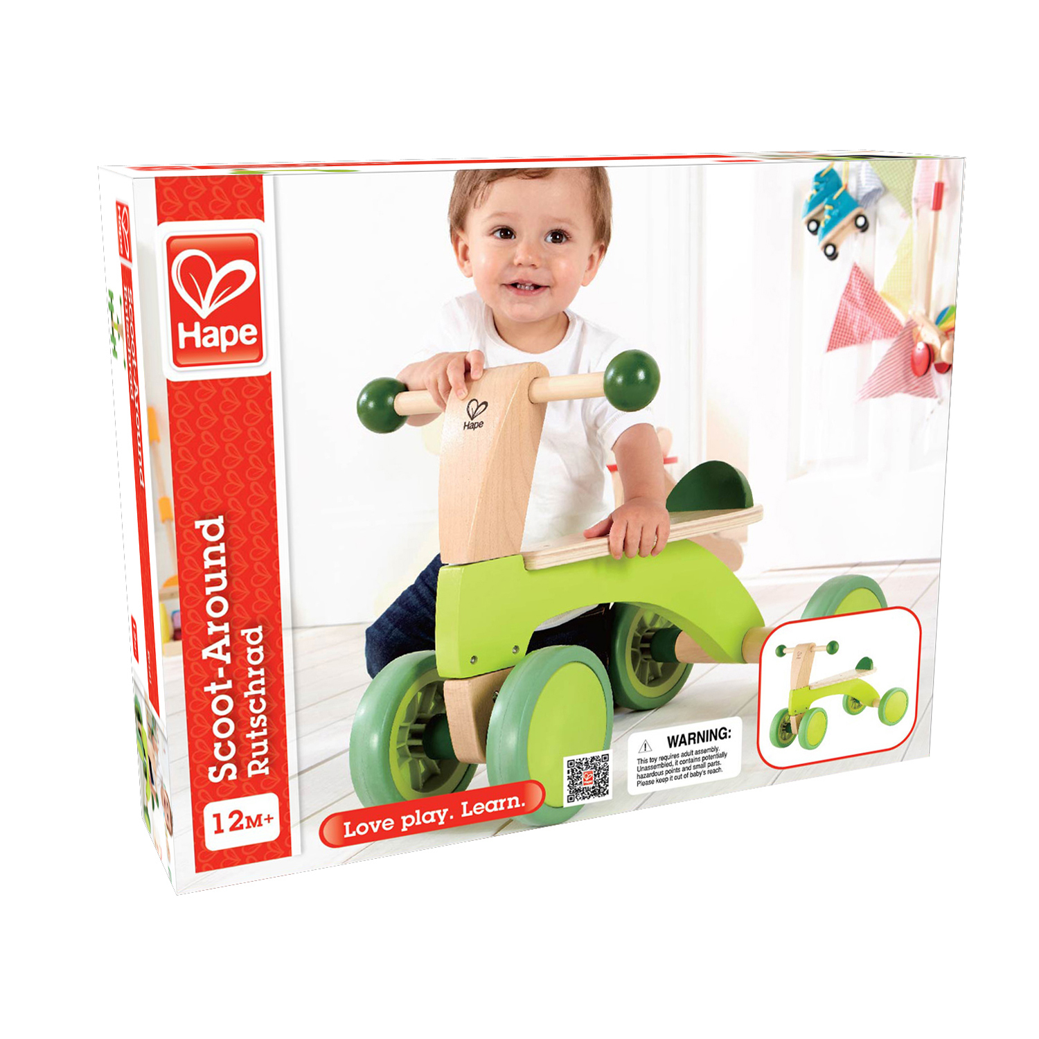 Un bambino su un giocattolo Scoot-Around verde e di legno. La scatola è sullo sfondo.