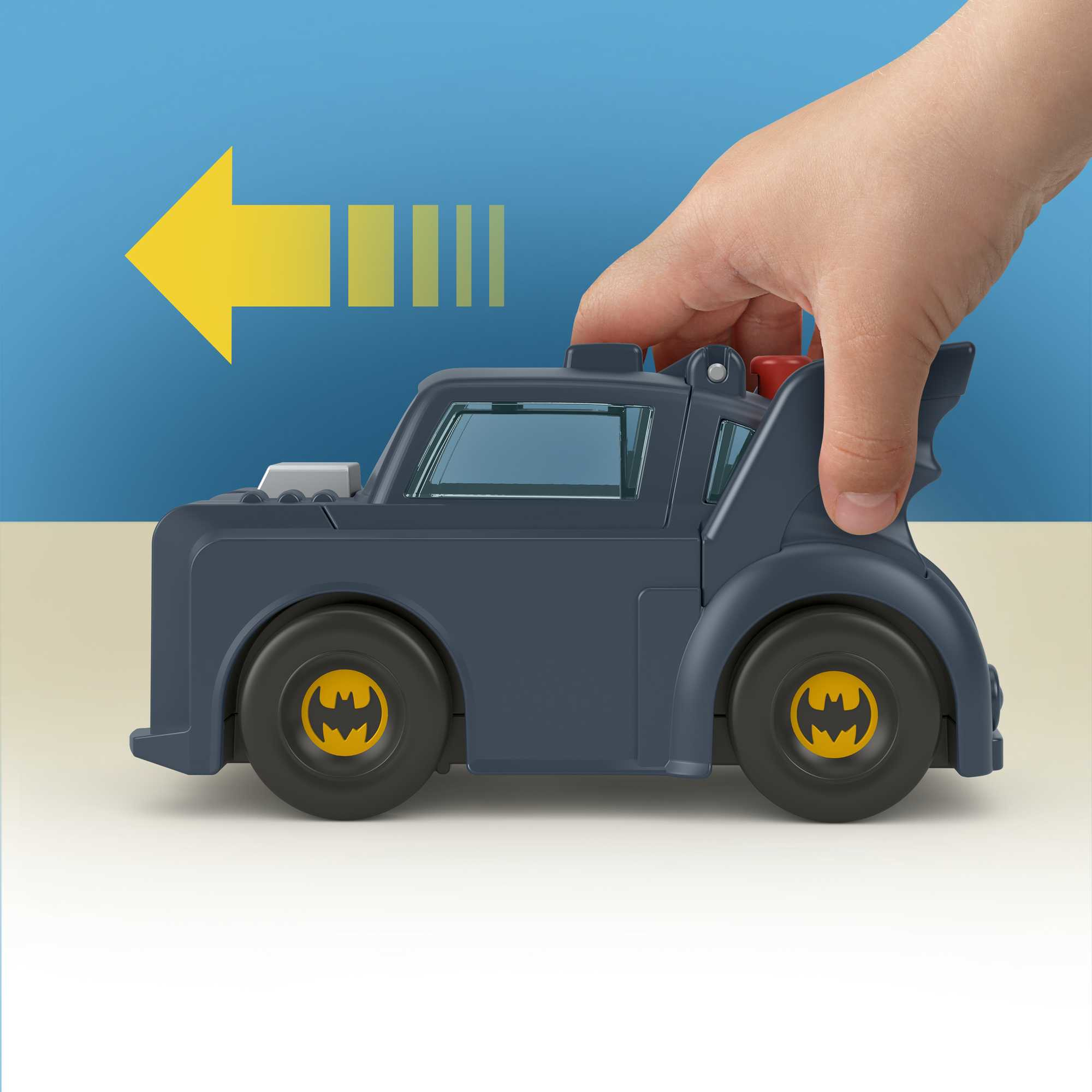 Ręka dziecka trzymająca ciemnoszarą zabawkę Batmobile. Widoczna żółta strzałka i niebieskie tło.