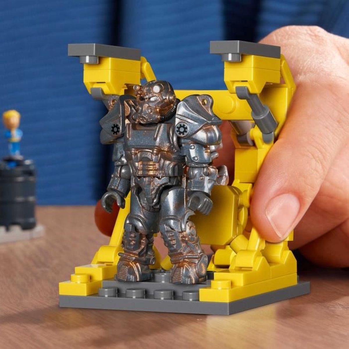 Una figura Lego grigia e gialla con un casco. Una piccola figura è sullo sfondo.
