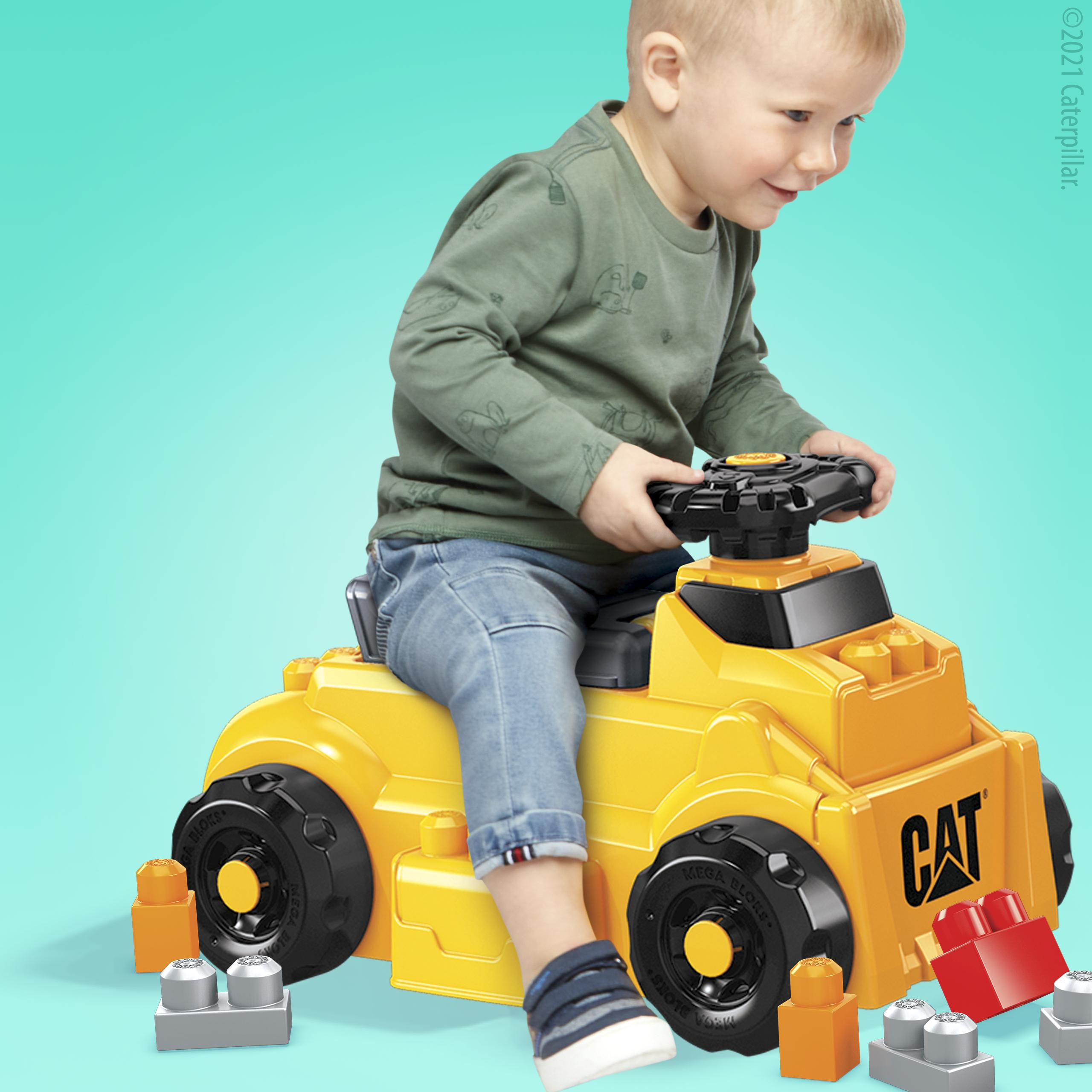 Un bambino su un camion giocattolo giallo con ruote nere e blocchi colorati.