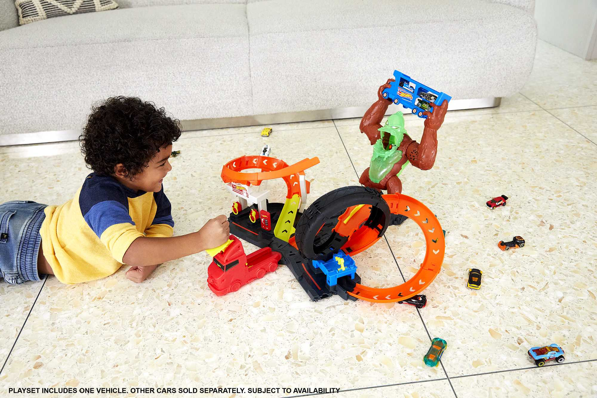 Dziecko bawi się zestawem torów Hot Wheels, w tym pętlą i figurą goryla.