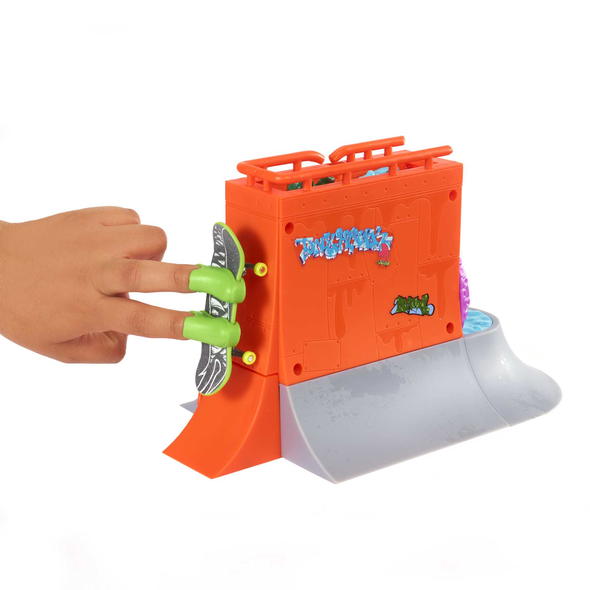 Dłoń używająca butów do jazdy na palcach na rampie. Pomarańczowa rampa z graffiti i małym basenem.