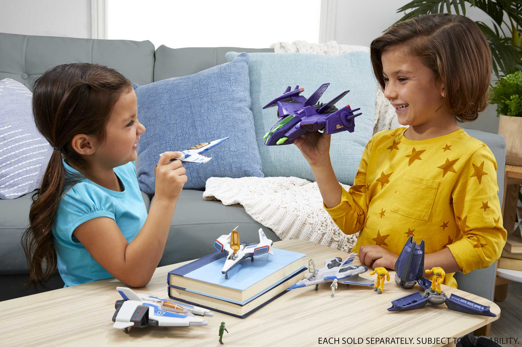 Dwoje dzieci bawiących się zabawkami-odrzutowcami kosmicznymi. Jeden z fioletowym, drugi z białym.