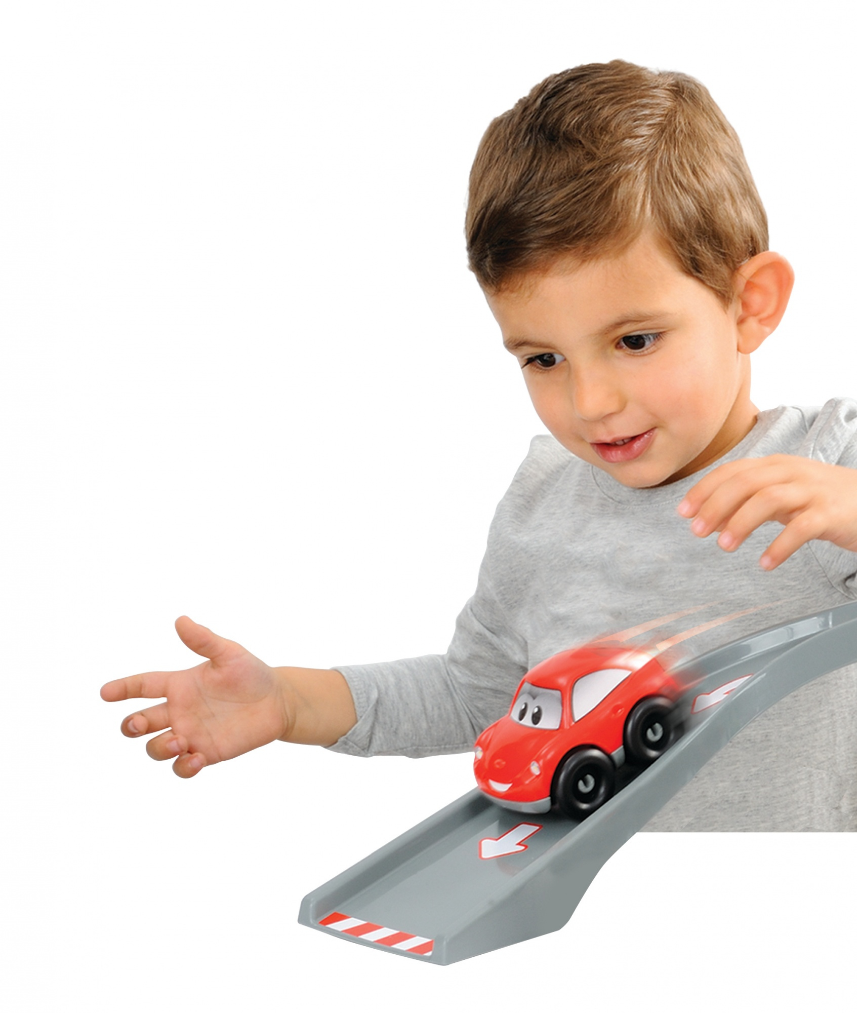 Chłopiec obserwuje, jak czerwony samochodzik zjeżdża po szarej rampie.