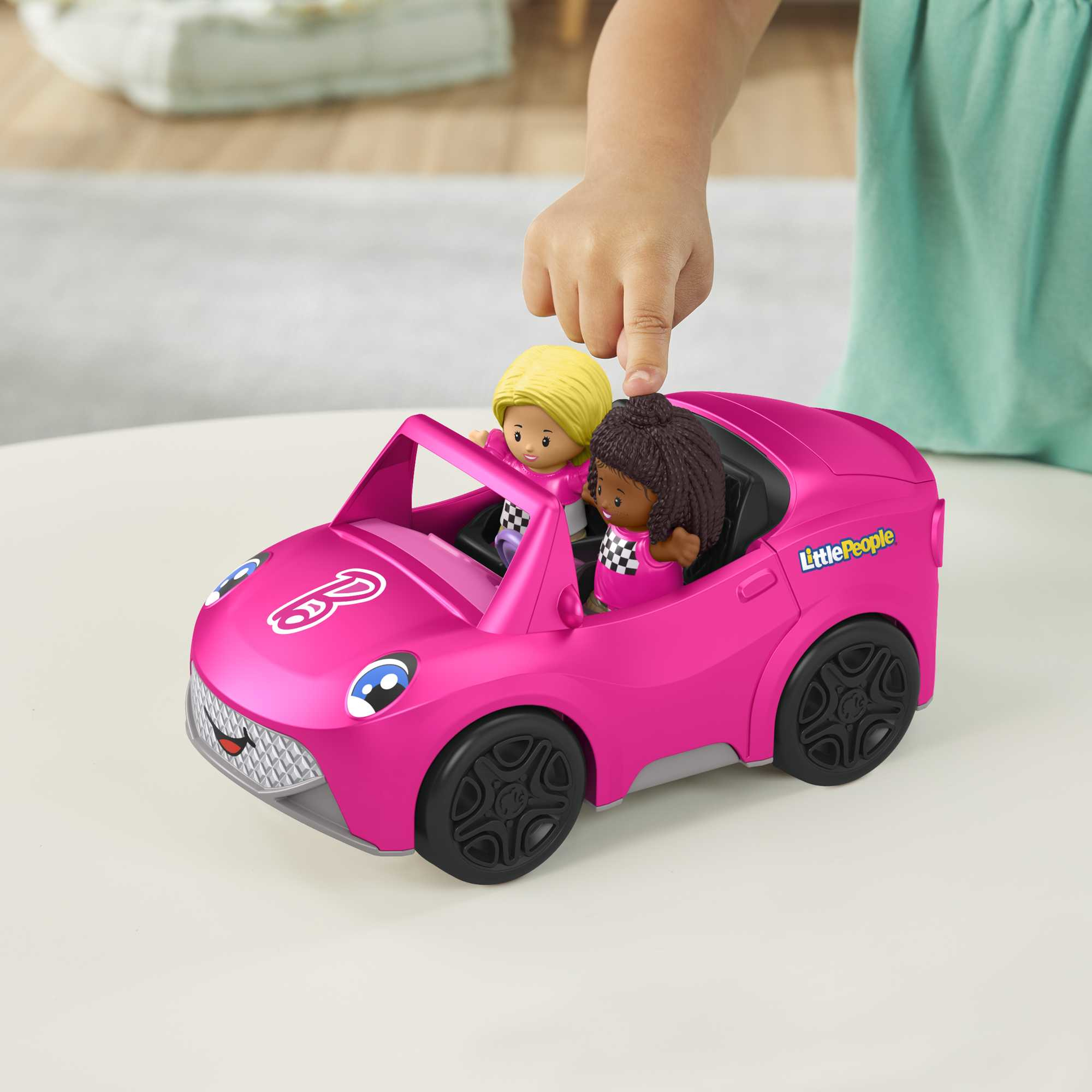 Coche de juguete rosa con dos figuras de juguete dentro sobre fondo blanco.