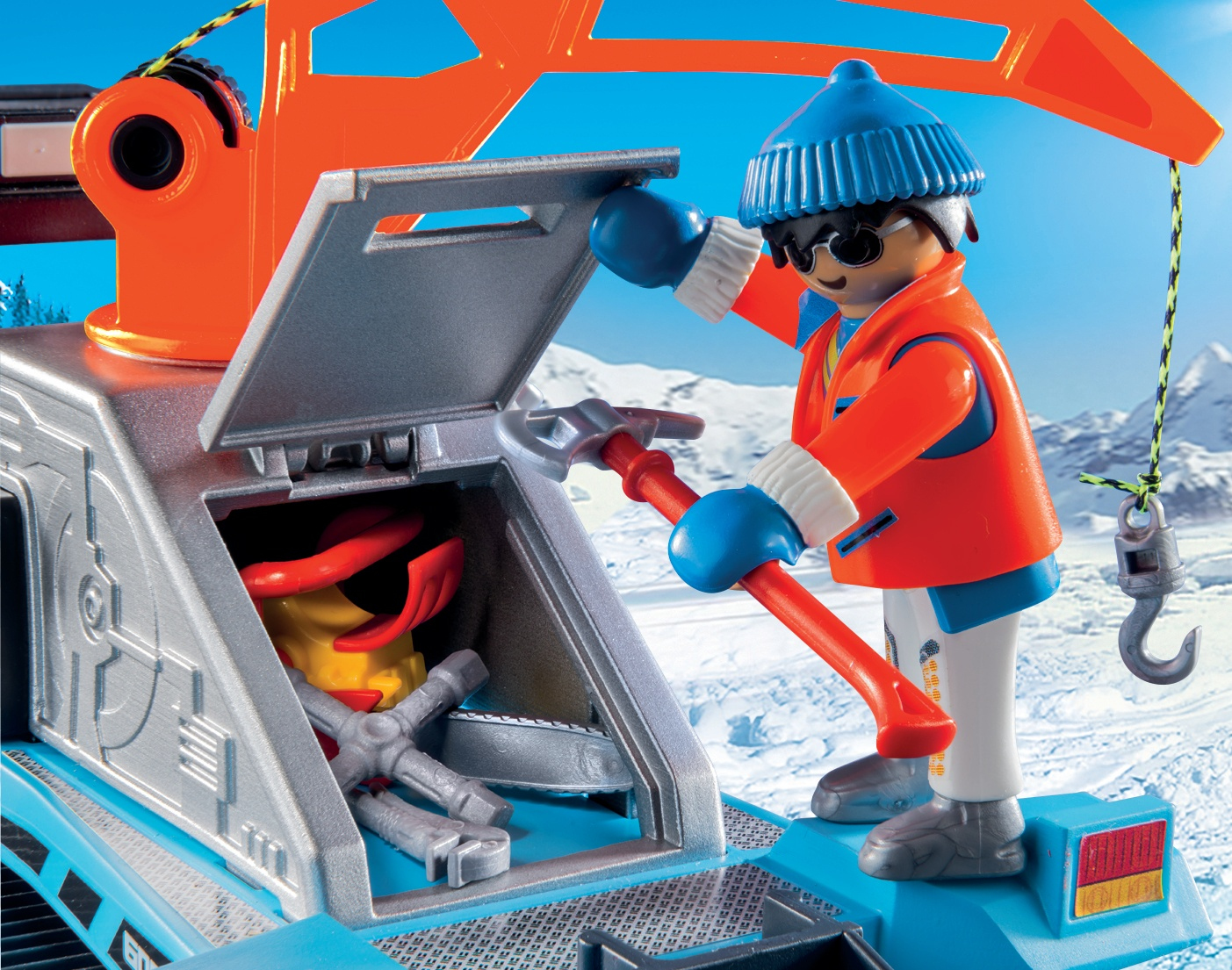 Figurka Playmobil z narzędziami w pobliżu pługa śnieżnego. Scena rozgrywa się w ośnieżonym górskim otoczeniu.