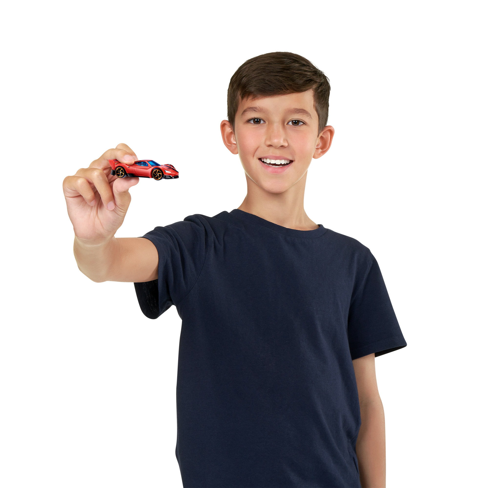 Chłopiec trzyma czerwony samochodzik, uśmiecha się i patrzy w kamerę.