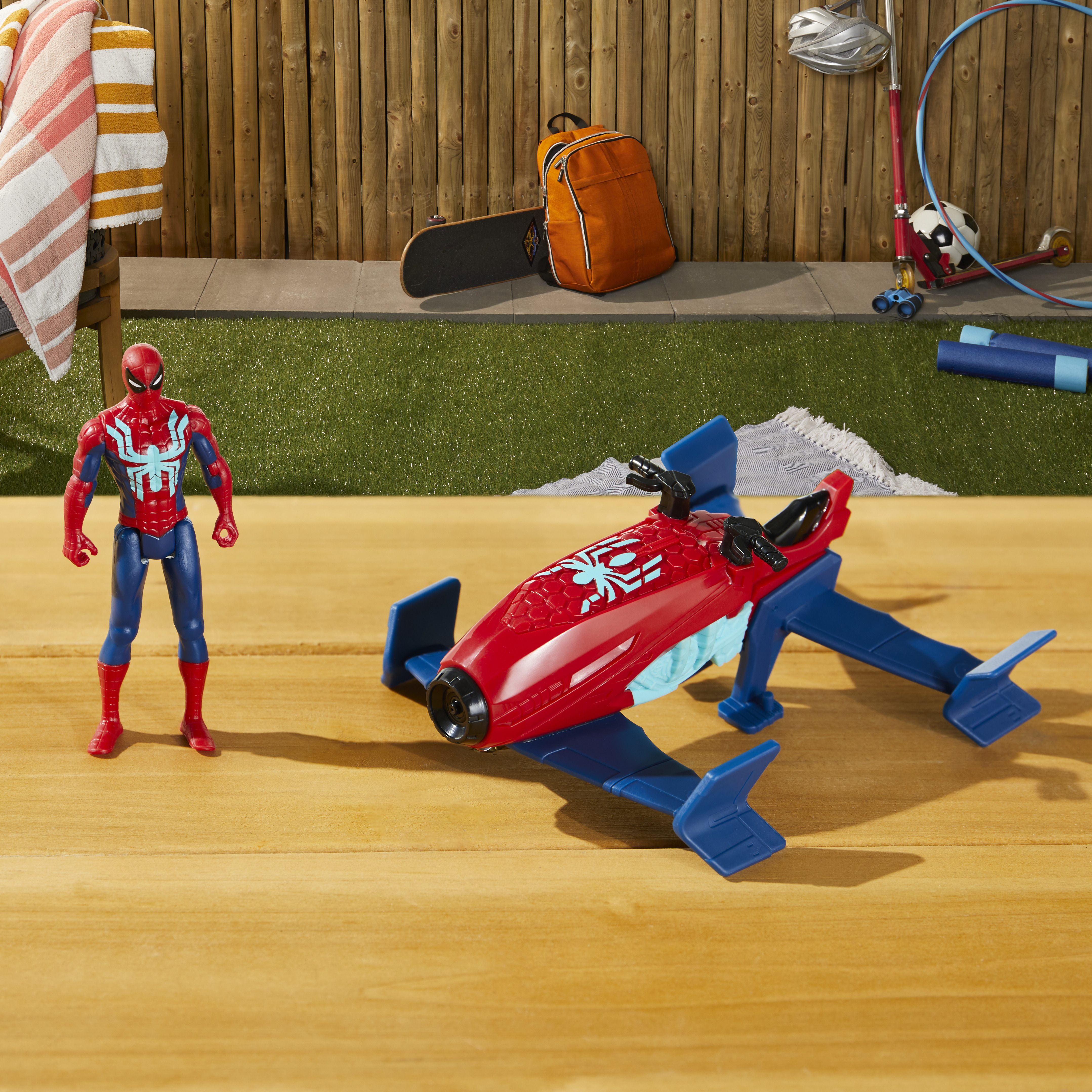 Figura de Spider-Man y vehículo tipo aerodeslizador sobre superficie de madera con objetos de fondo.