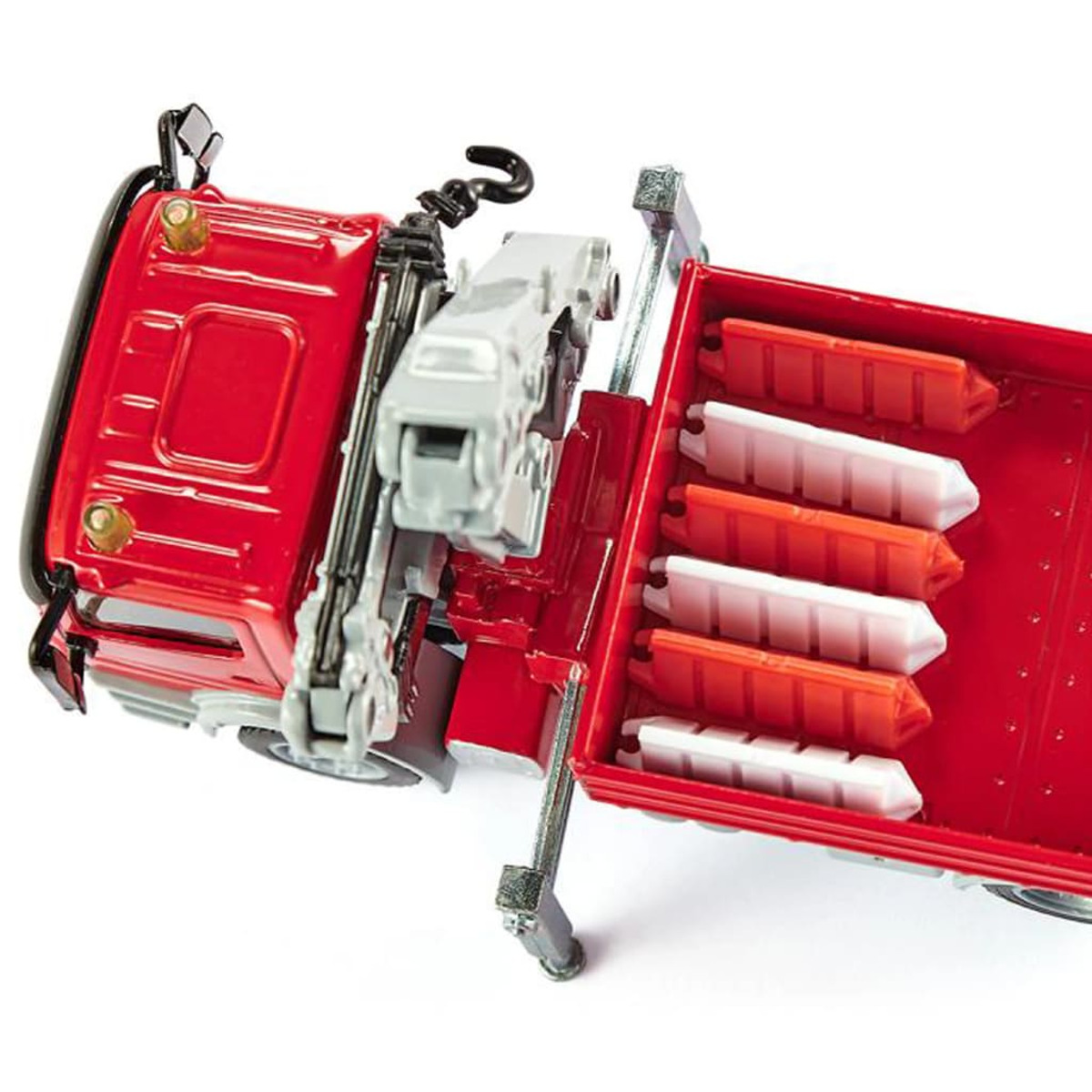 Zbliżenie czerwonej zabawki ciężarówki z dźwigiem i ładunkiem białych i czerwonych barier ochronnych.