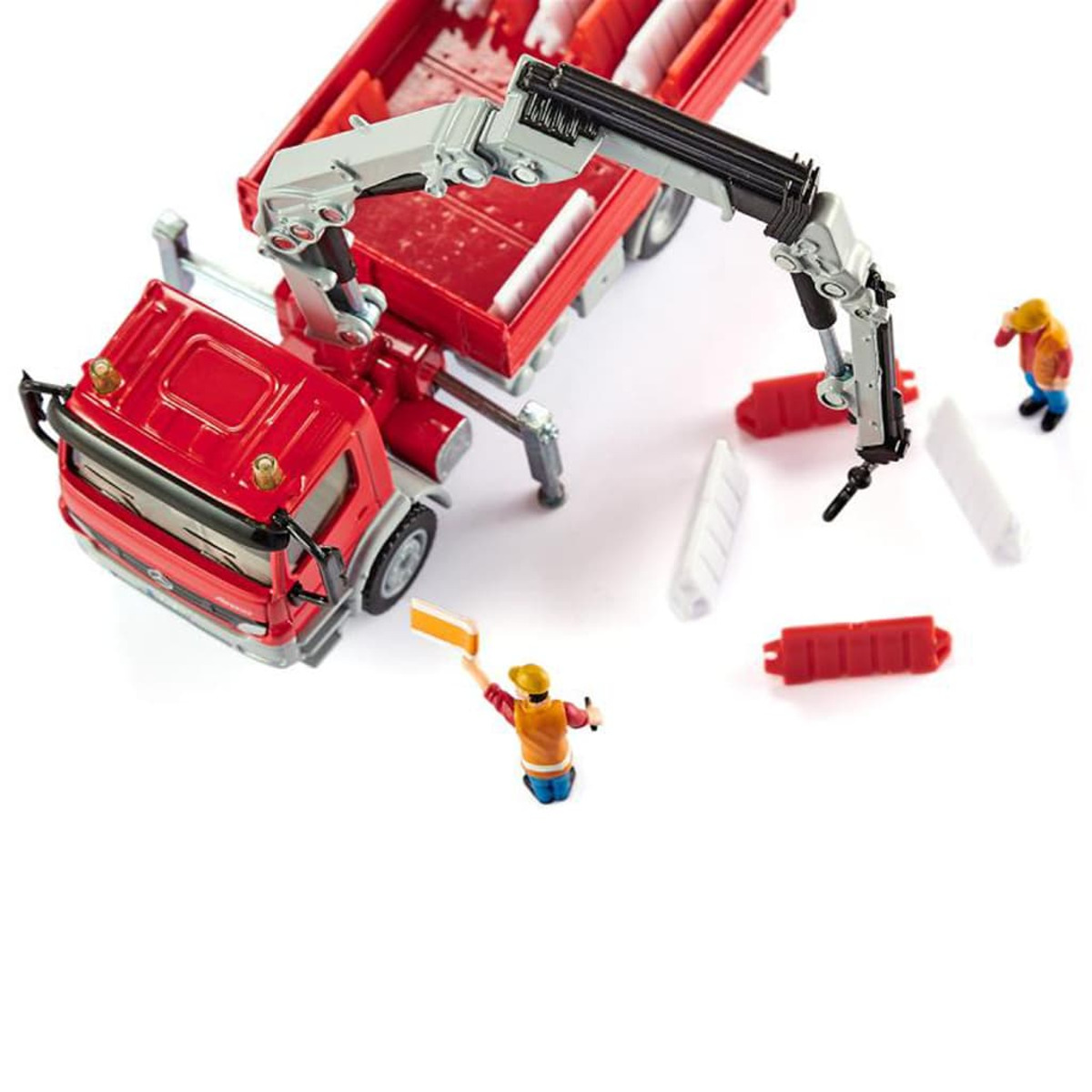 Czerwona zabawka ciężarówka z żurawiem, robotnikami i barierami. Scena na białym.