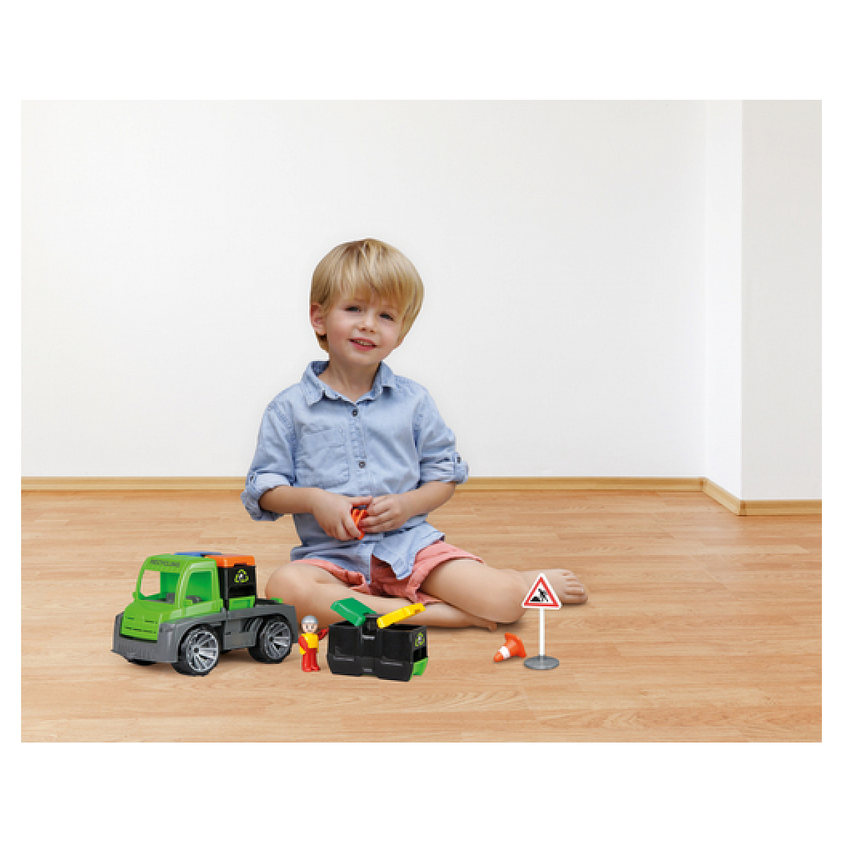 Chłopiec bawi się zieloną zabawką ciężarówką w pobliżu znaku.