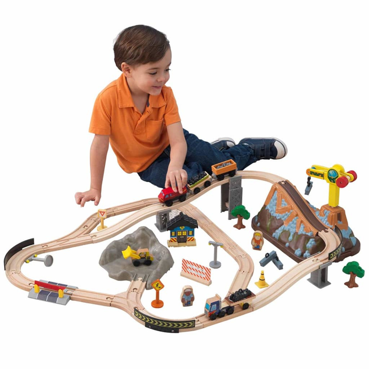 Dziecko bawiące się drewnianym zestawem kolejki. Zestaw zawiera tory, pociągi i różne budynki.