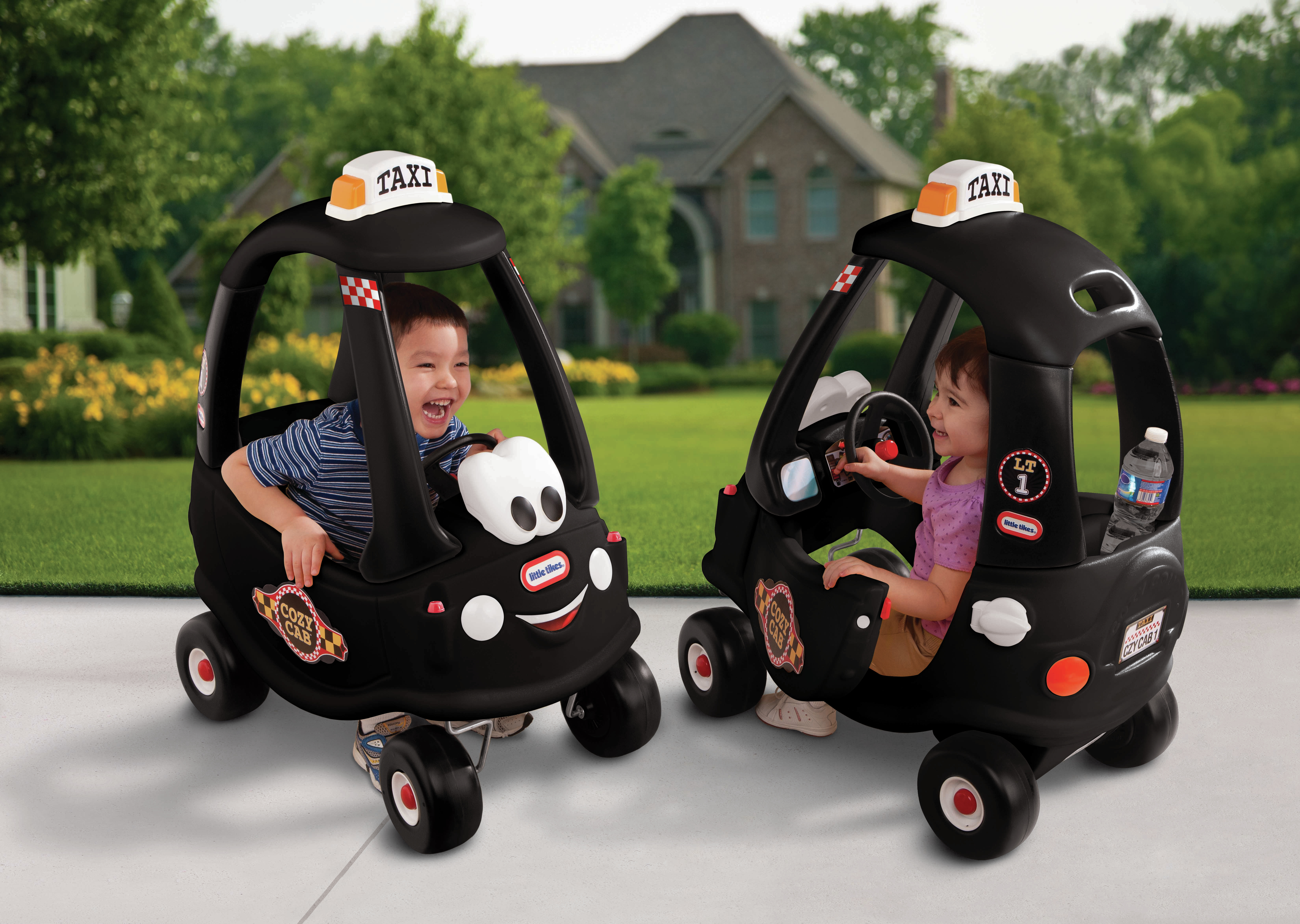 Due taxi giocattolo neri con bambini sorridenti dentro, uno con volante.