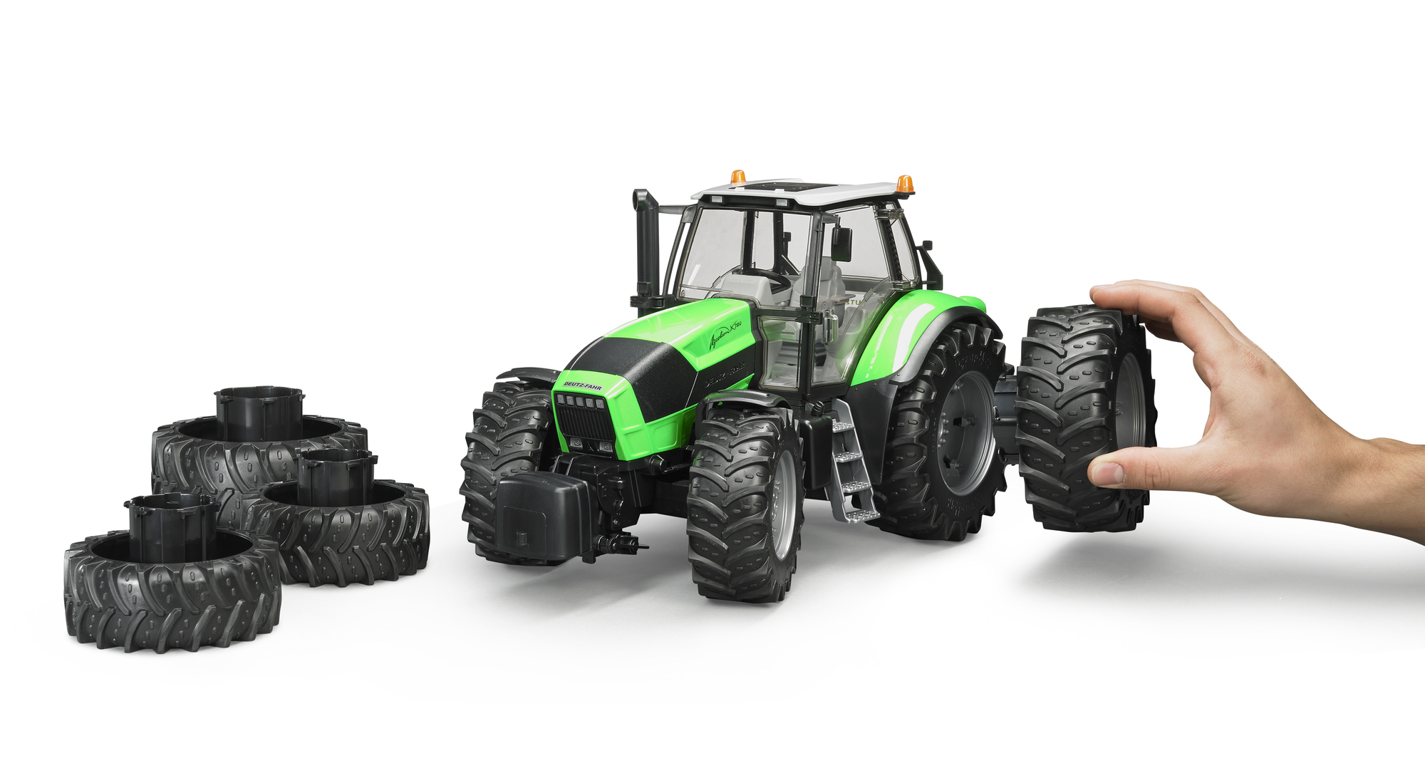 Zielony traktor z dłonią trzymającą opony. Białe tło.