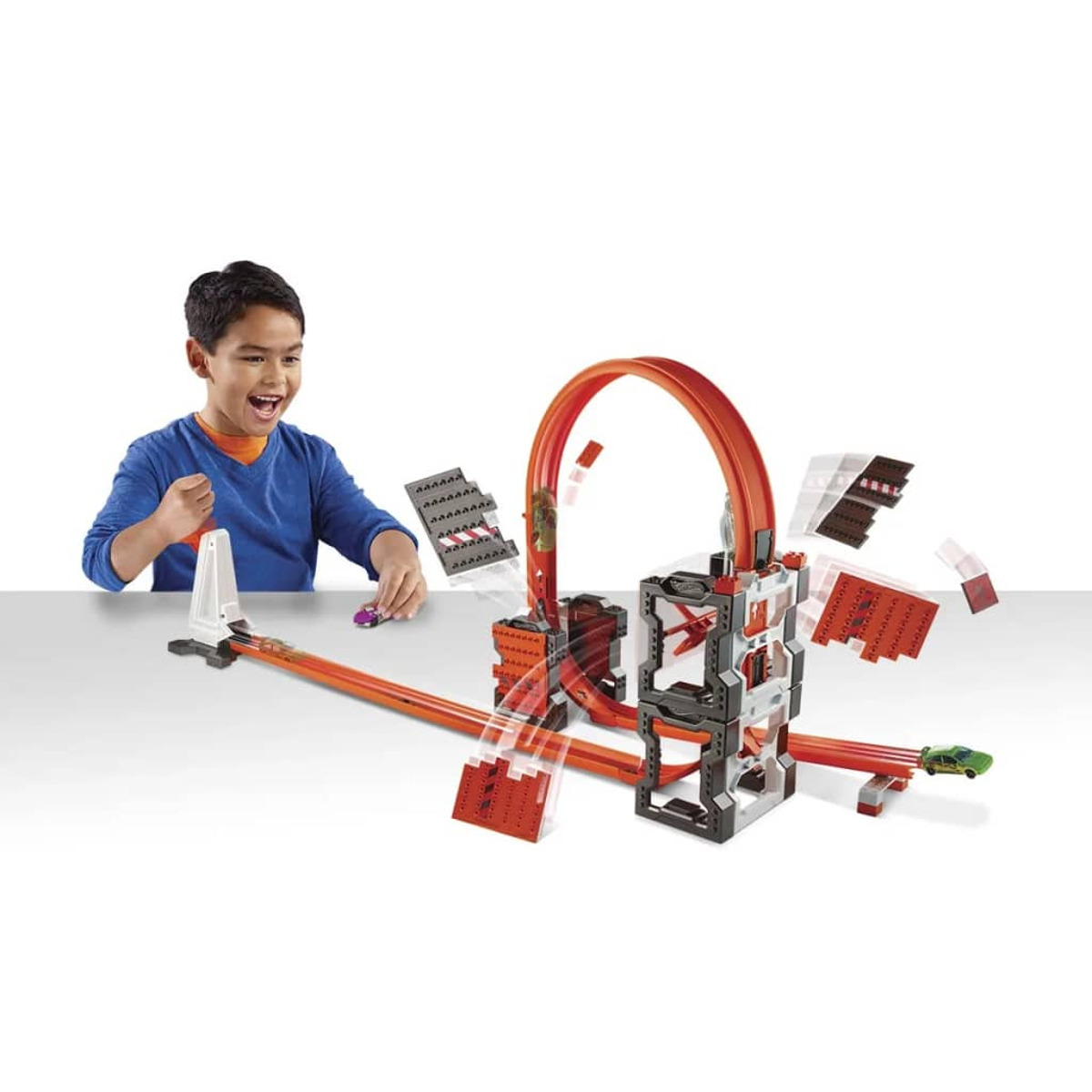Chłopiec bawiący się torem wyścigowym. Tor ma pętlę i wieżę.