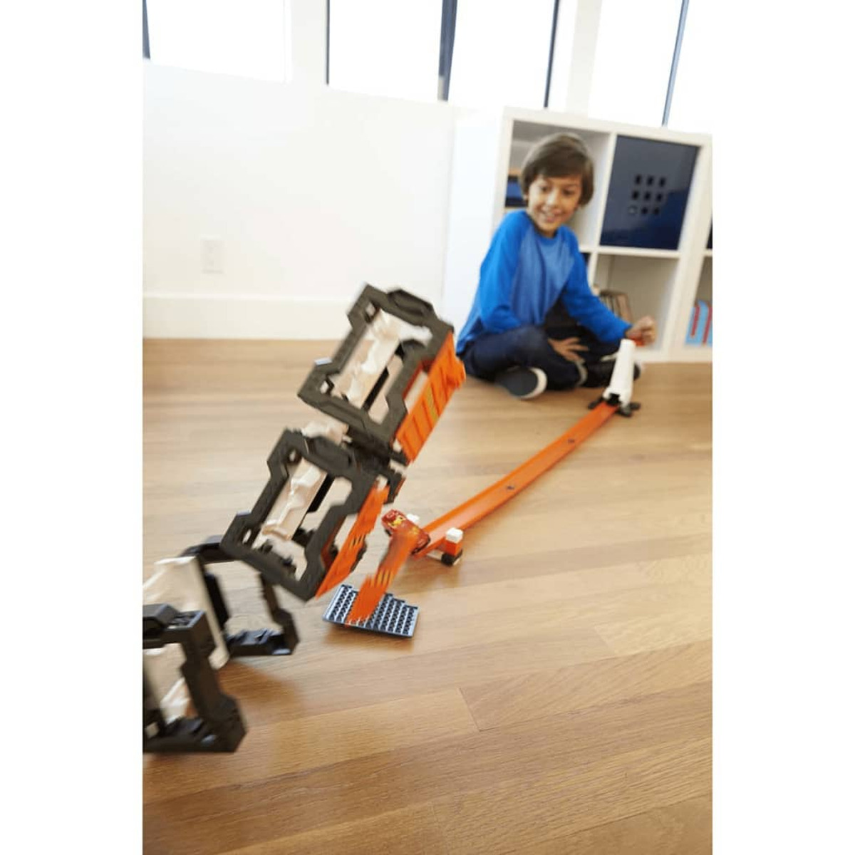 Chłopiec bawi się torem wyścigowym. Tor jest pomarańczowy i ma wieżę.