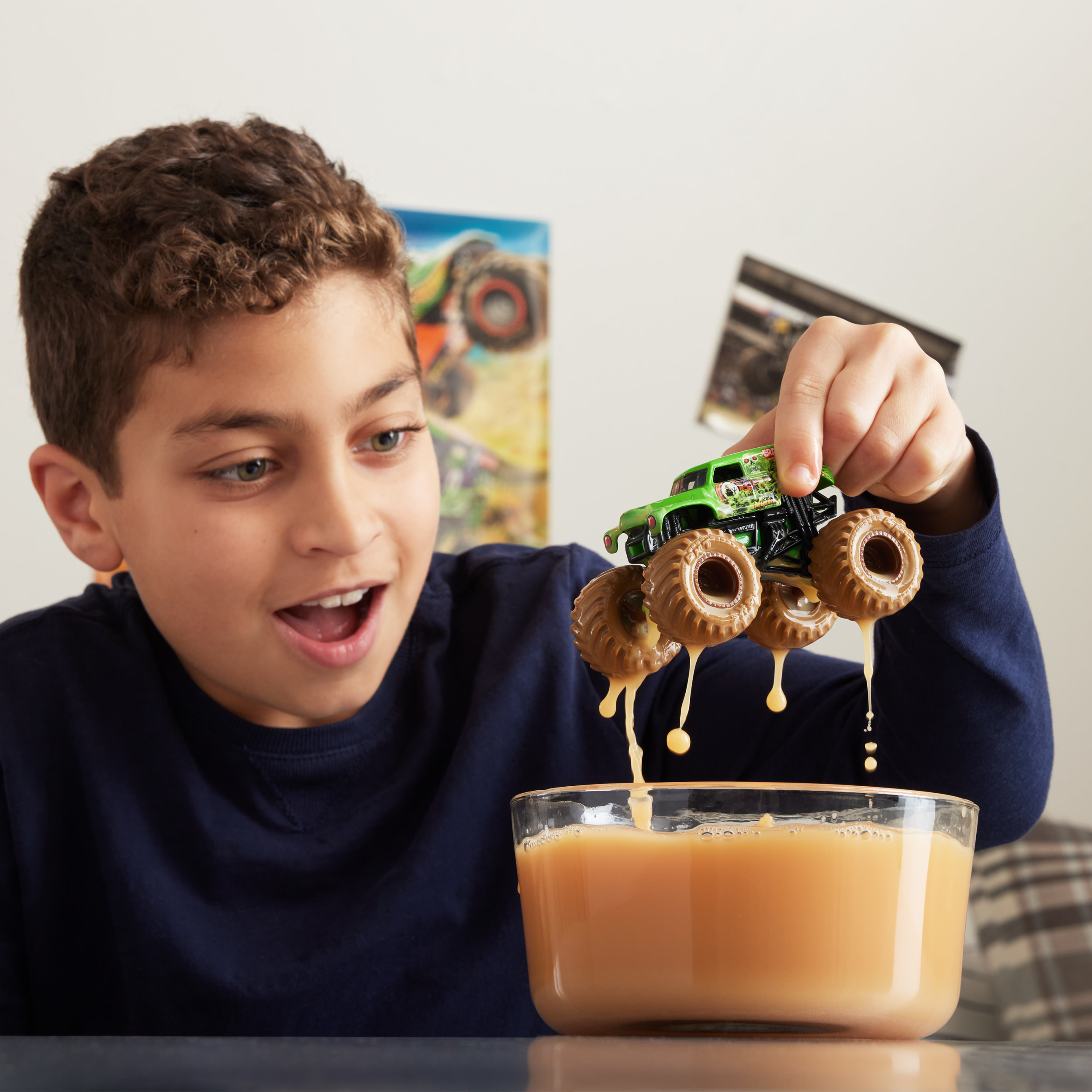 Chłopiec trzyma zielonego monster trucka nad miską, powodując kapanie cieczy do środka.