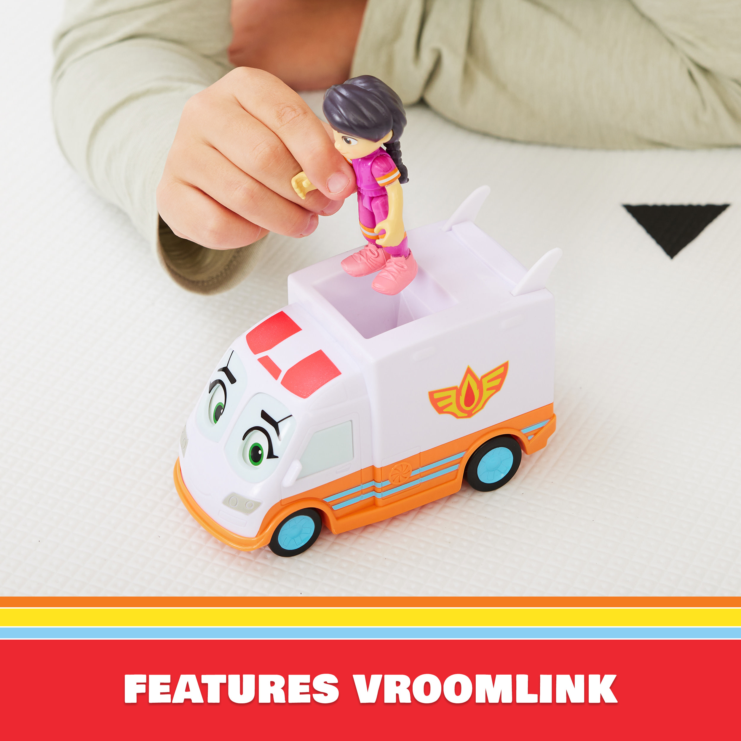 Dziecko wchodzi w interakcję z zabawką karetką. Karetka jest biało-pomarańczowa z figurką na górze.