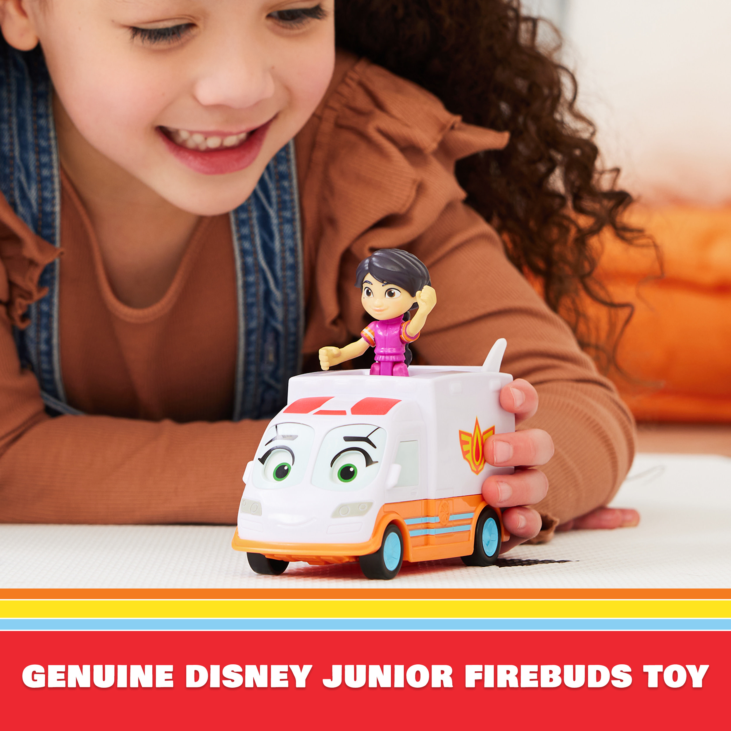 Dziewczynka bawiąca się zabawką karetką. Tekst poniżej: 'GENUINE DISNEY JUNIOR FIREBUDS TOY'.