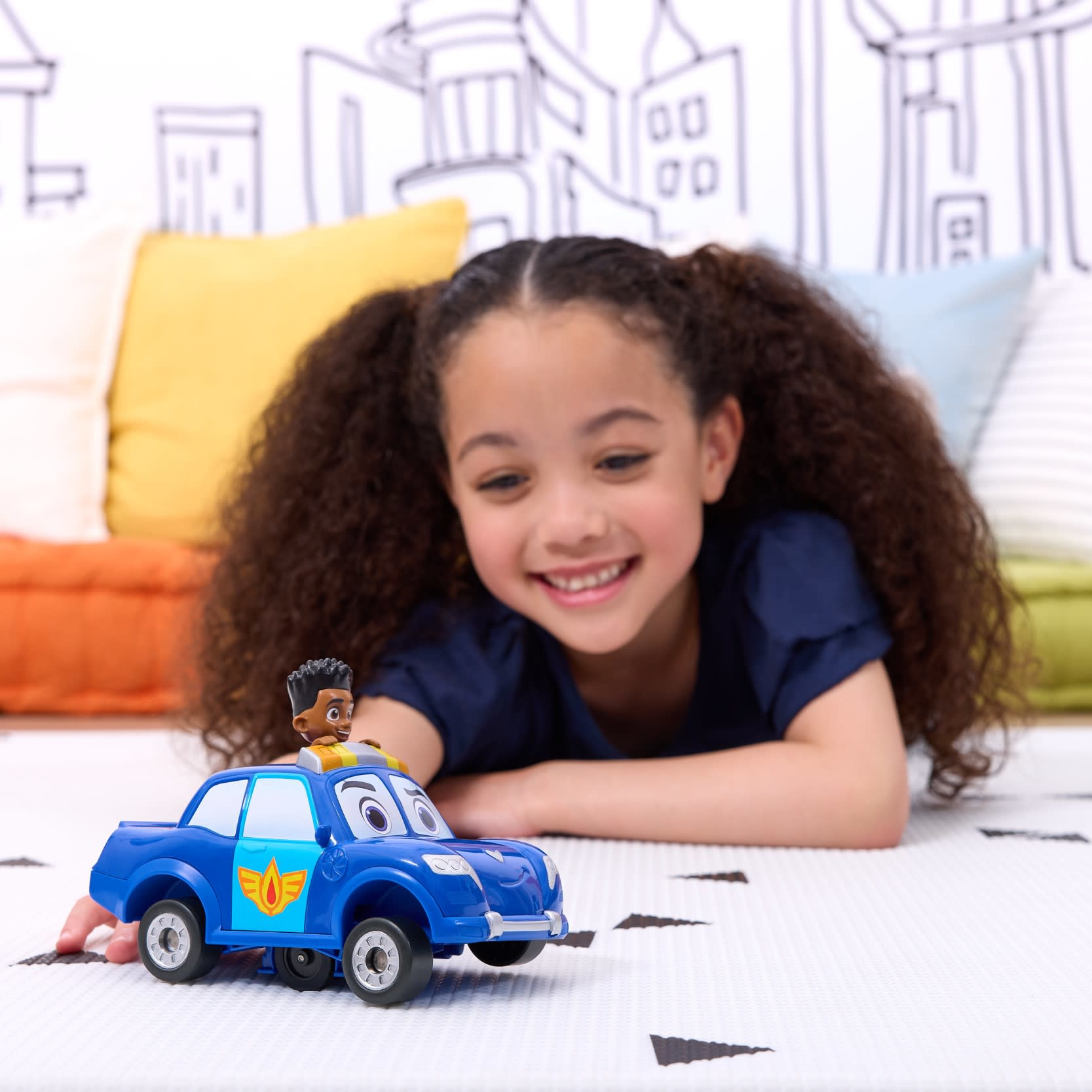 Młoda dziewczyna uśmiecha się, bawiąc się niebieskim samochodzikiem policyjnym. Na górze czarnoskóry ludzik.