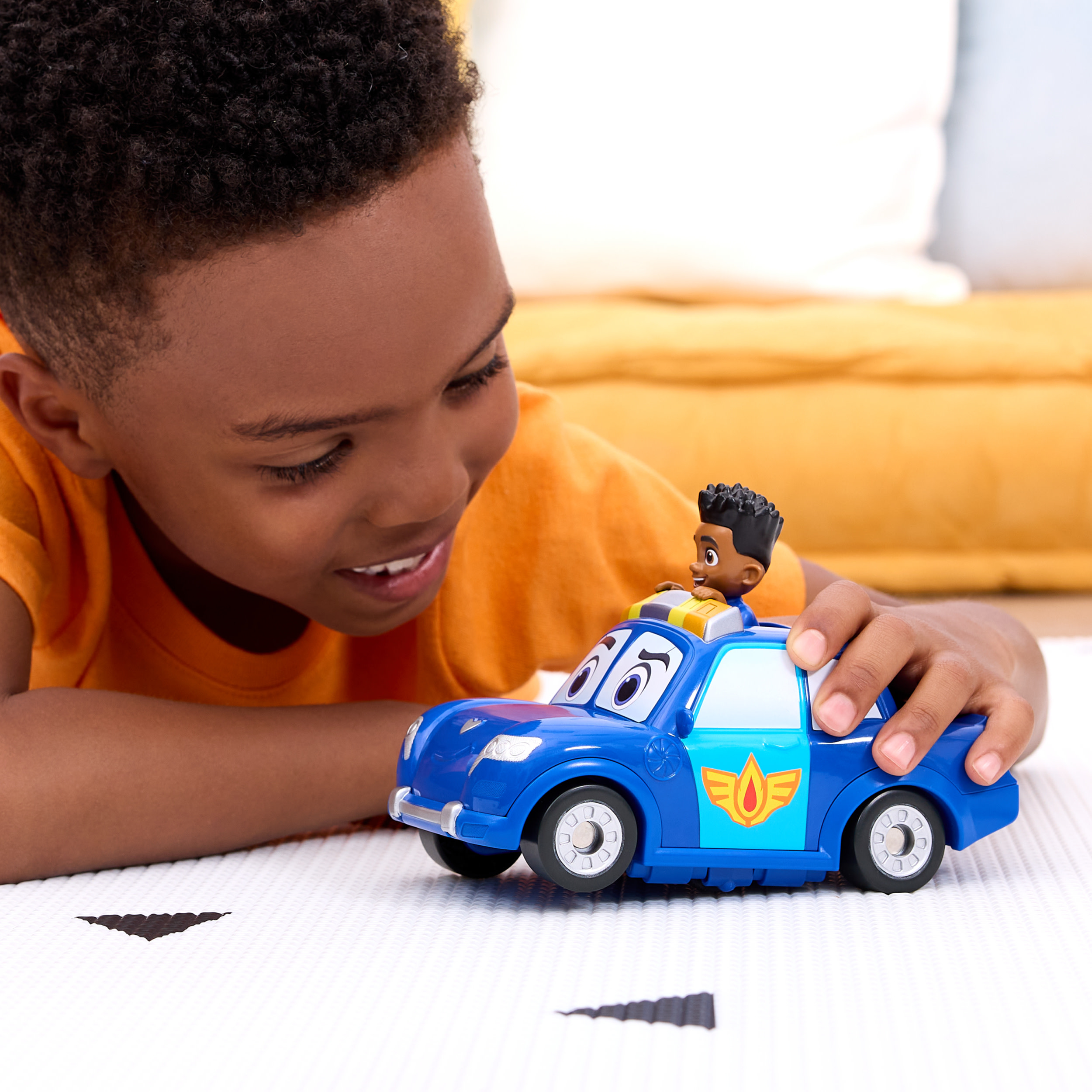 Mały chłopiec bawi się niebieskim samochodzikiem policyjnym. Czarnoskóry ludzik jest na dachu samochodu.