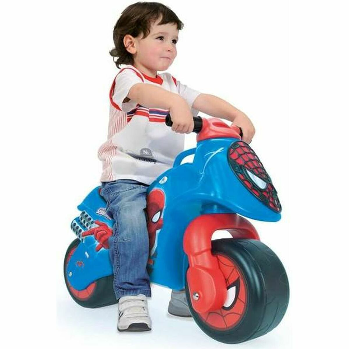 Un bambino piccolo guida una moto giocattolo blu e rossa a tema Spider-Man.